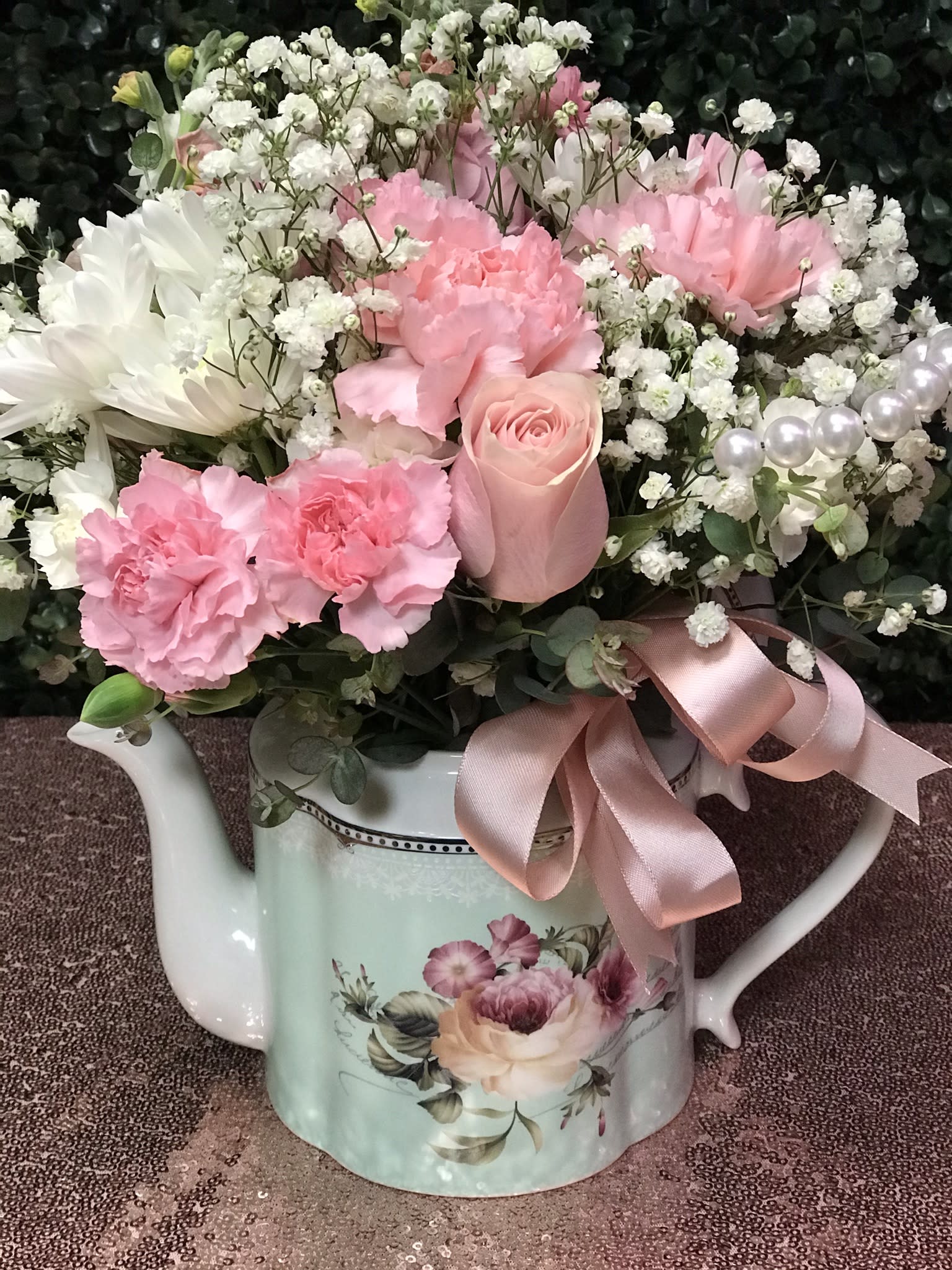 Pink and white flowers arranged in a decorative watering can