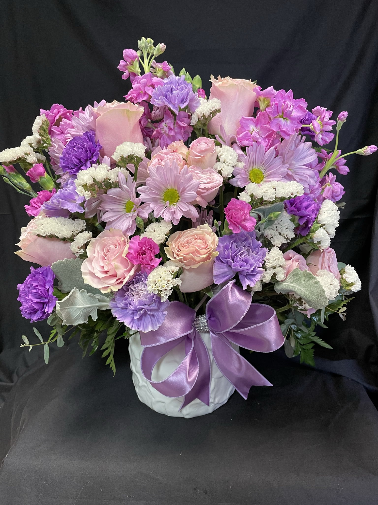 Pink and purple mixed bouquet in a white vase with a lavender ribbon