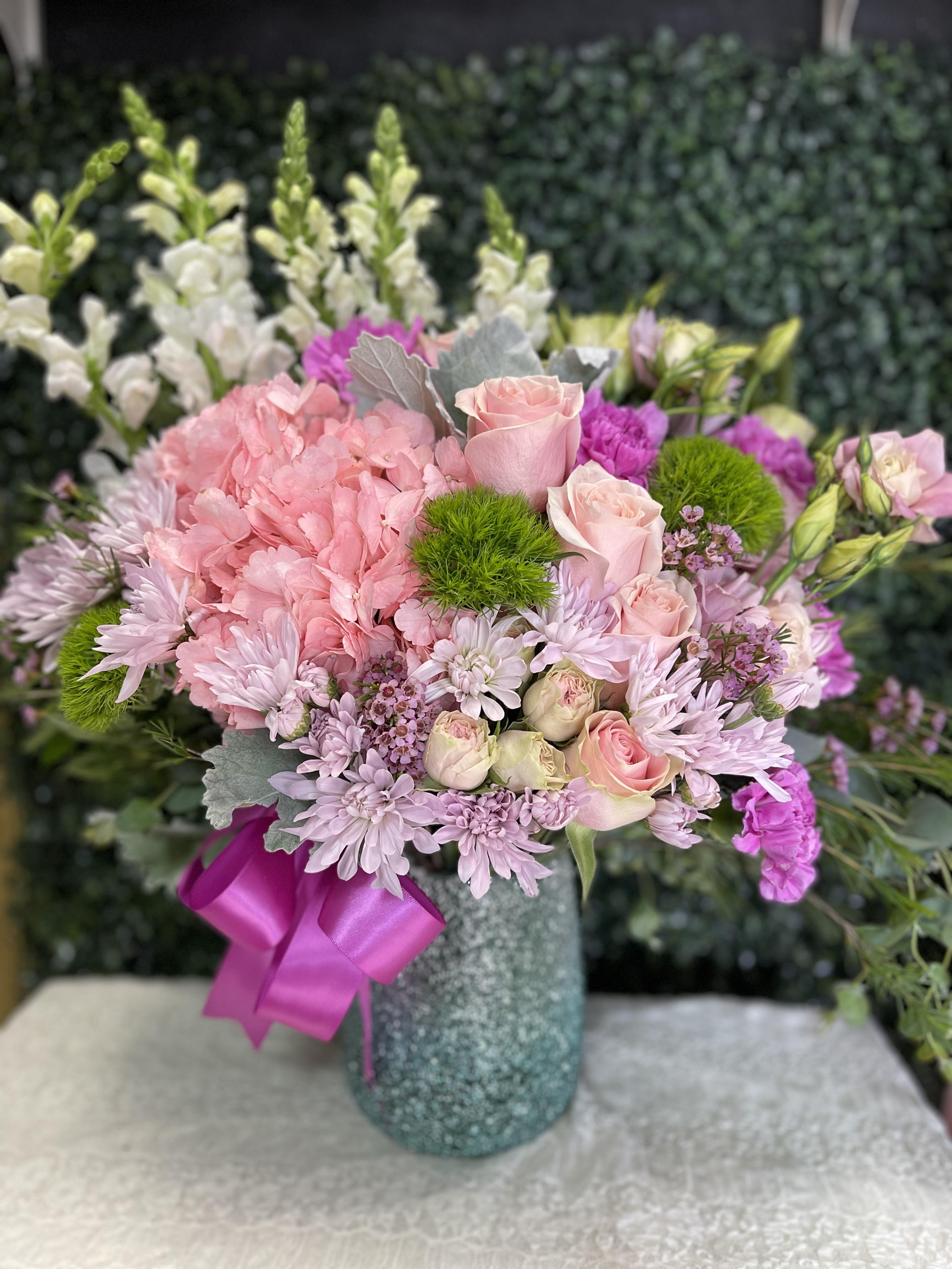 Pink and lavender bouquet in a textured vase with a magenta ribbon