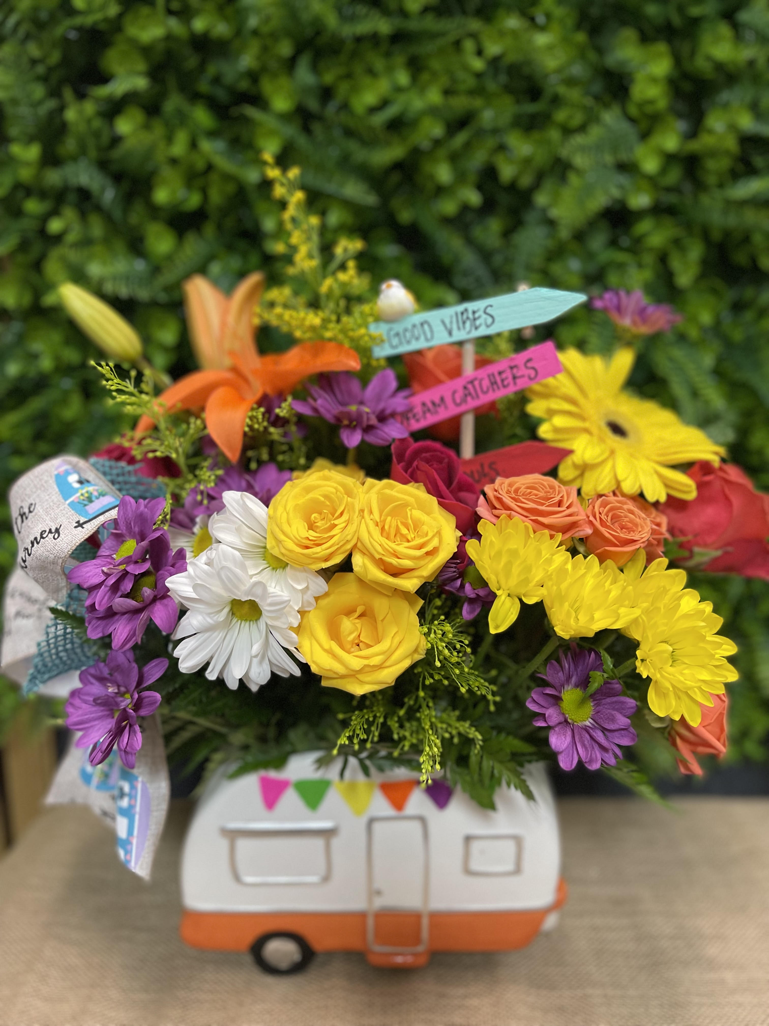 Colorful bouquet in a camper-shaped container with small sign picks