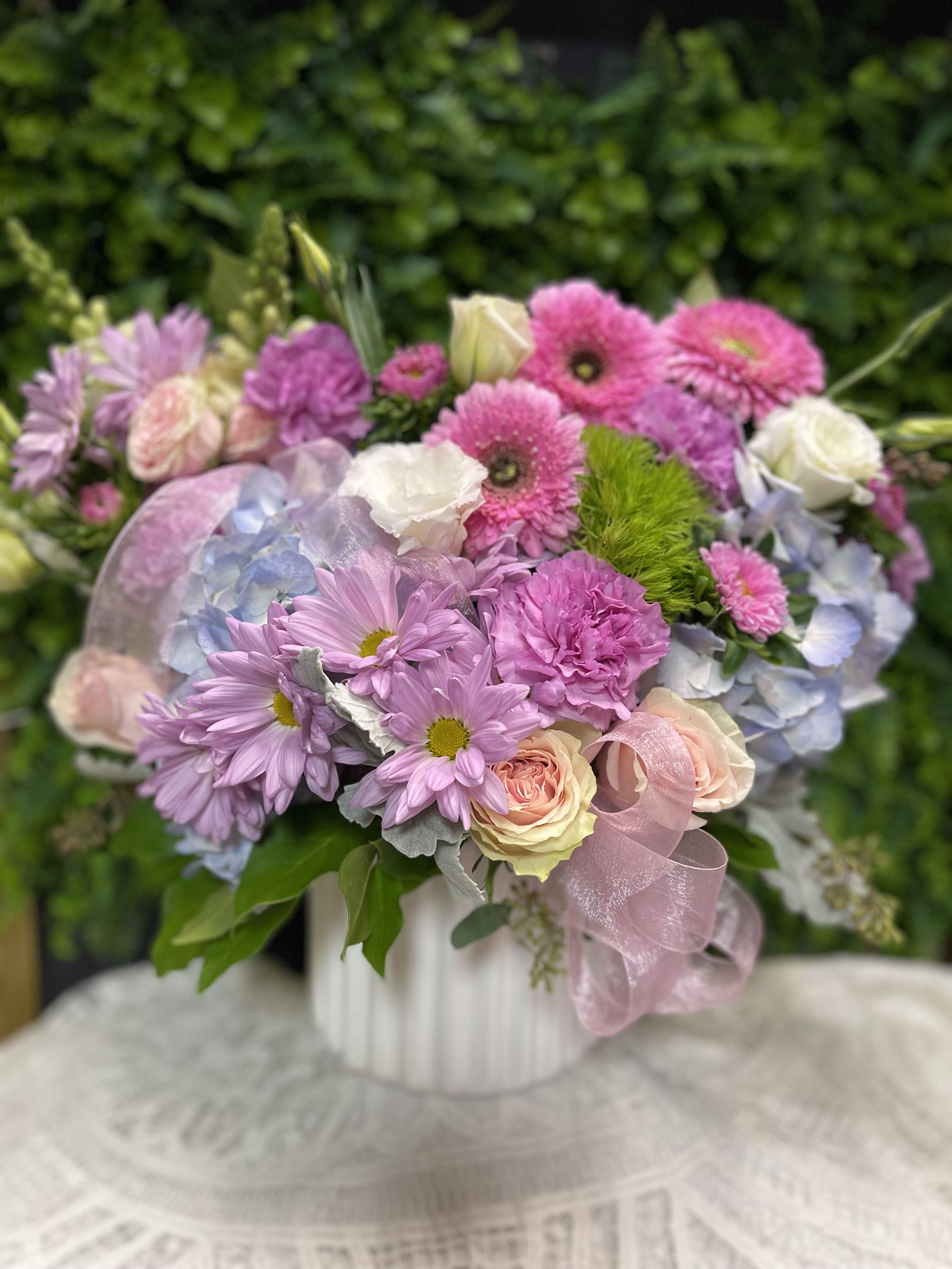Pink and lavender bouquet with roses, daisies, and hydrangea in a white vase