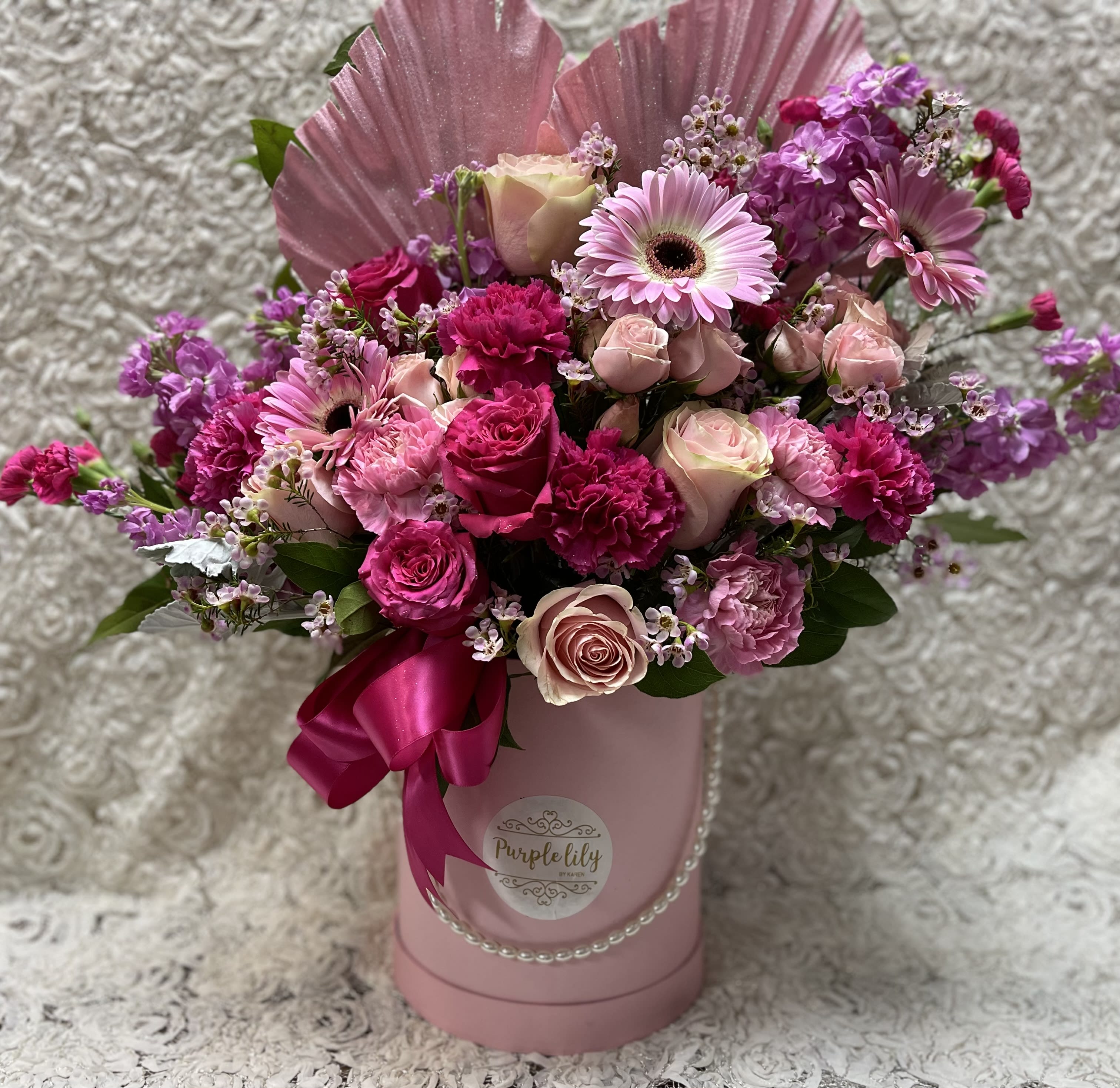Pink and purple mixed flower arrangement in a pink hatbox with ribbon