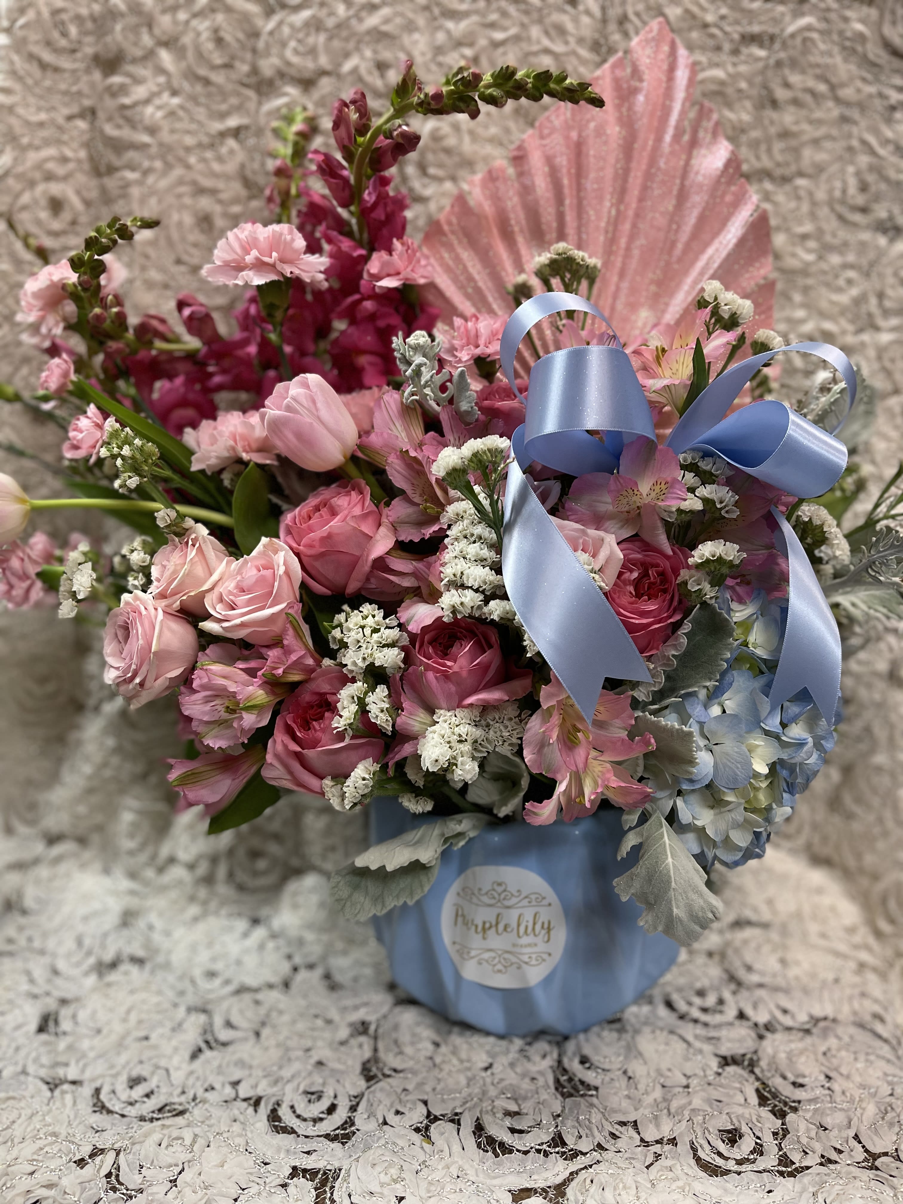 Pink roses and mixed flowers in a blue box with a ribbon