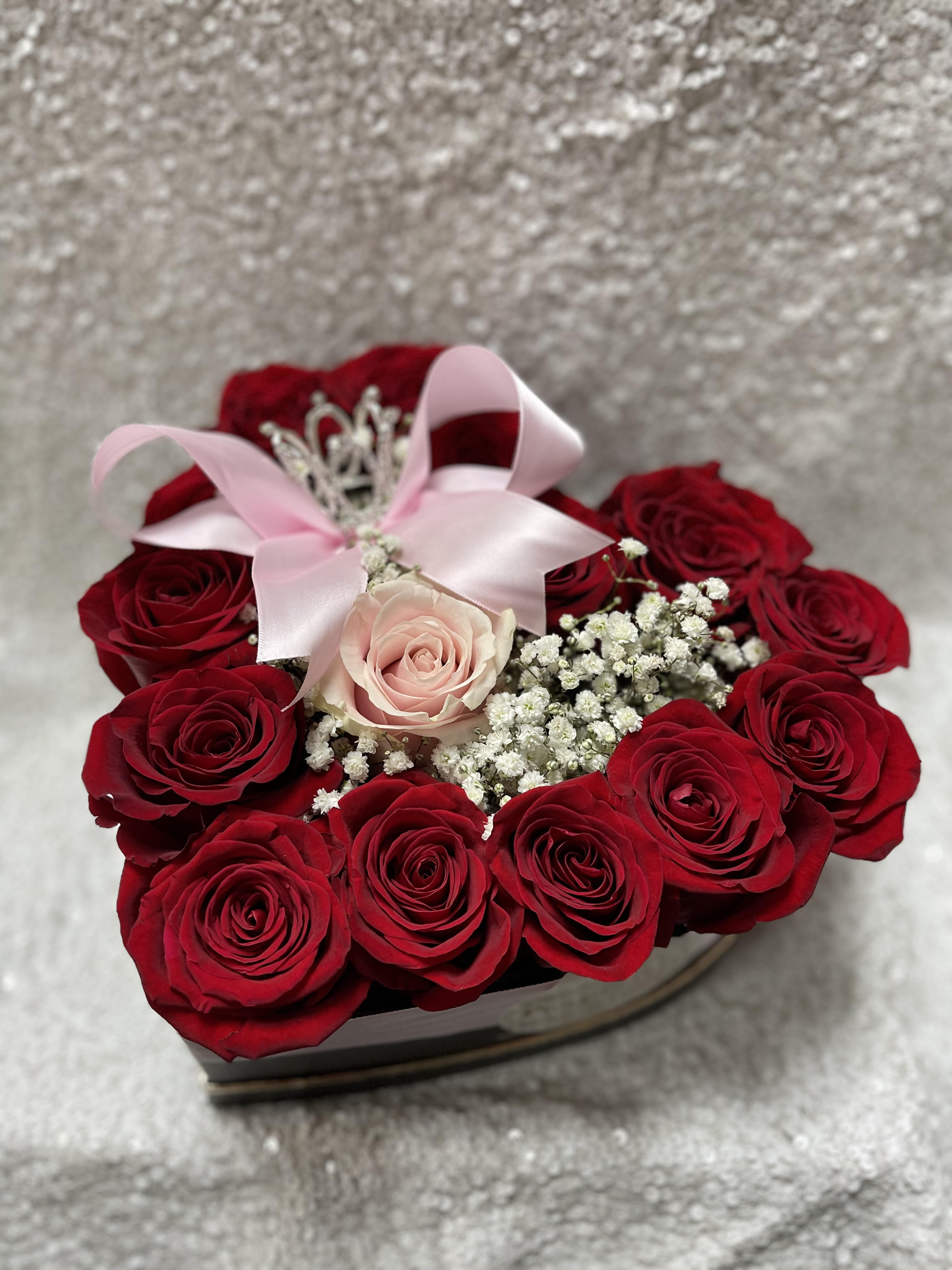 Heart-shaped box of red roses with a pink rose and ribbon bow