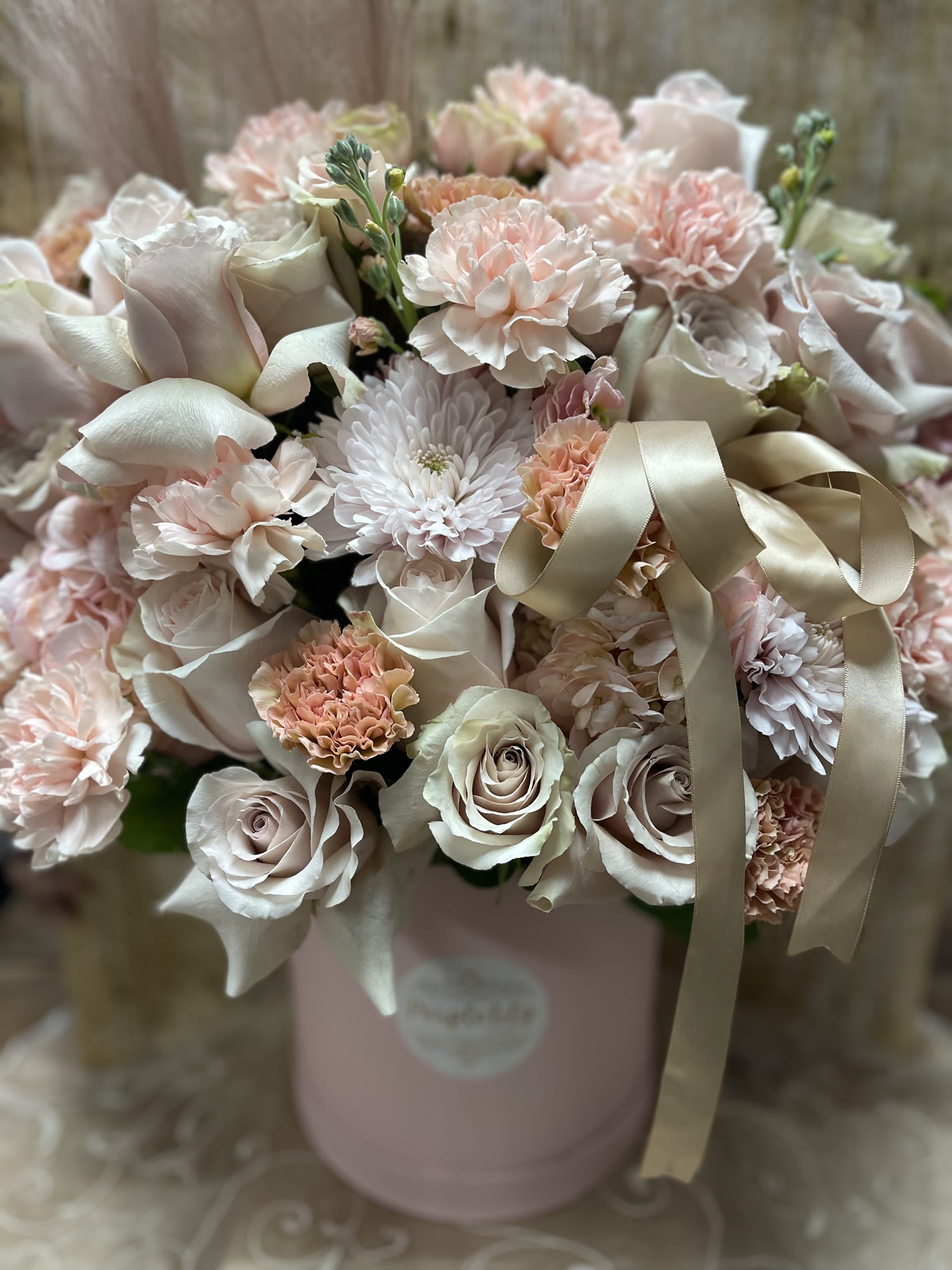 Blush and ivory bouquet of roses, carnations, and mums in a pink hatbox
