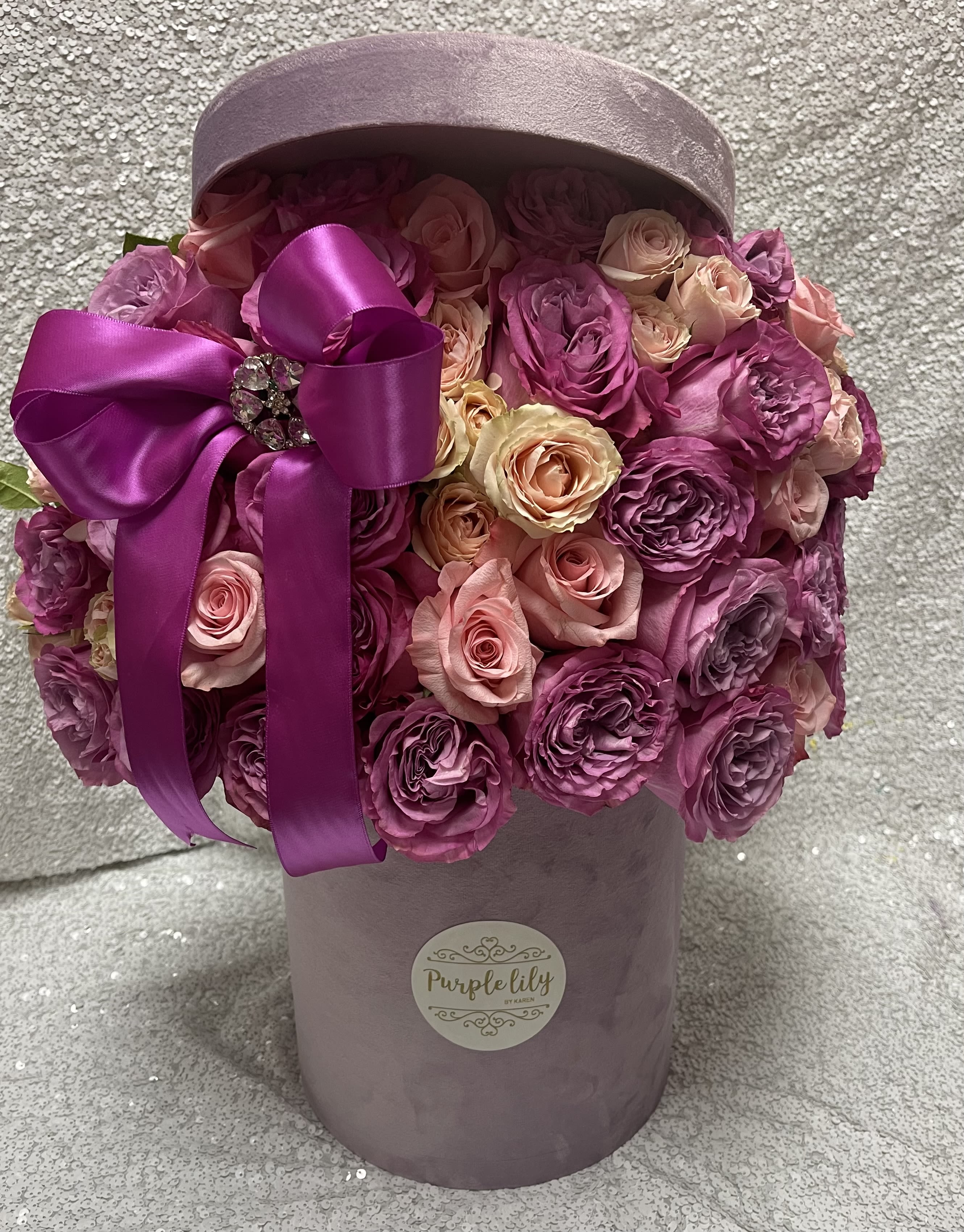 Pink and purple roses in a lavender hatbox with a satin ribbon