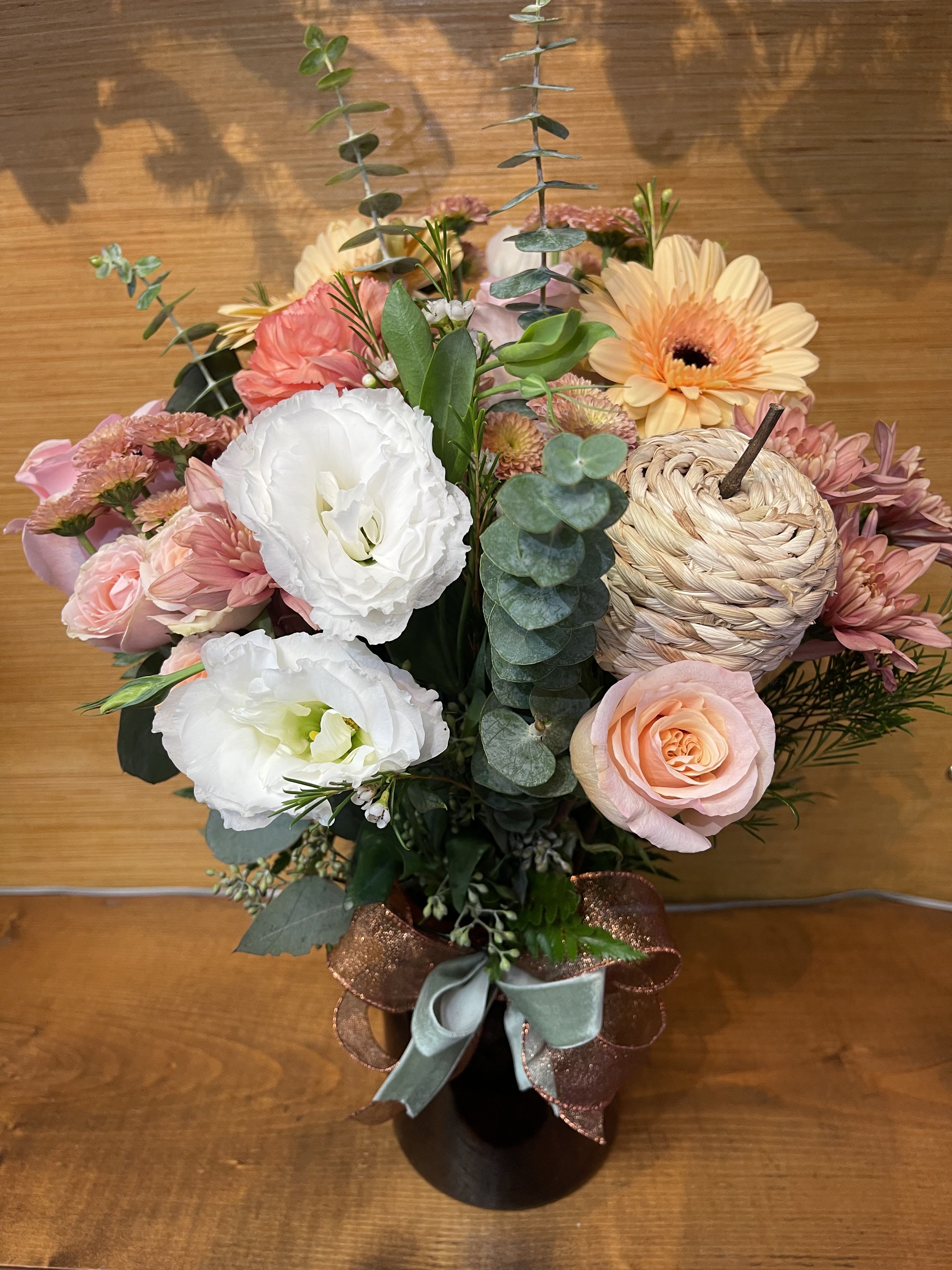 Pink and white mixed flower arrangement in a black vase with ribbon