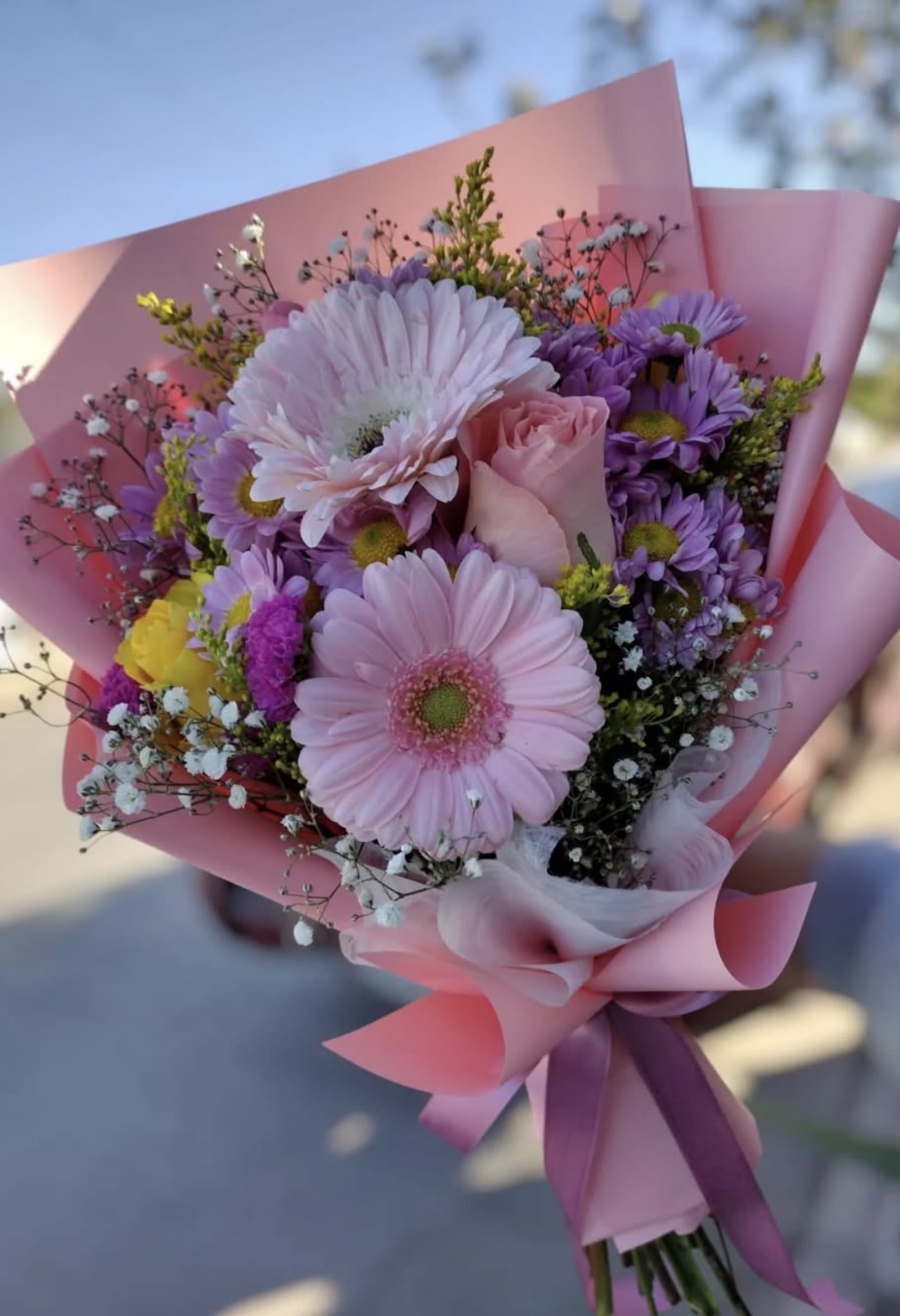 Pink and purple bouquet with gerbera daisies and a rose in pink wrap