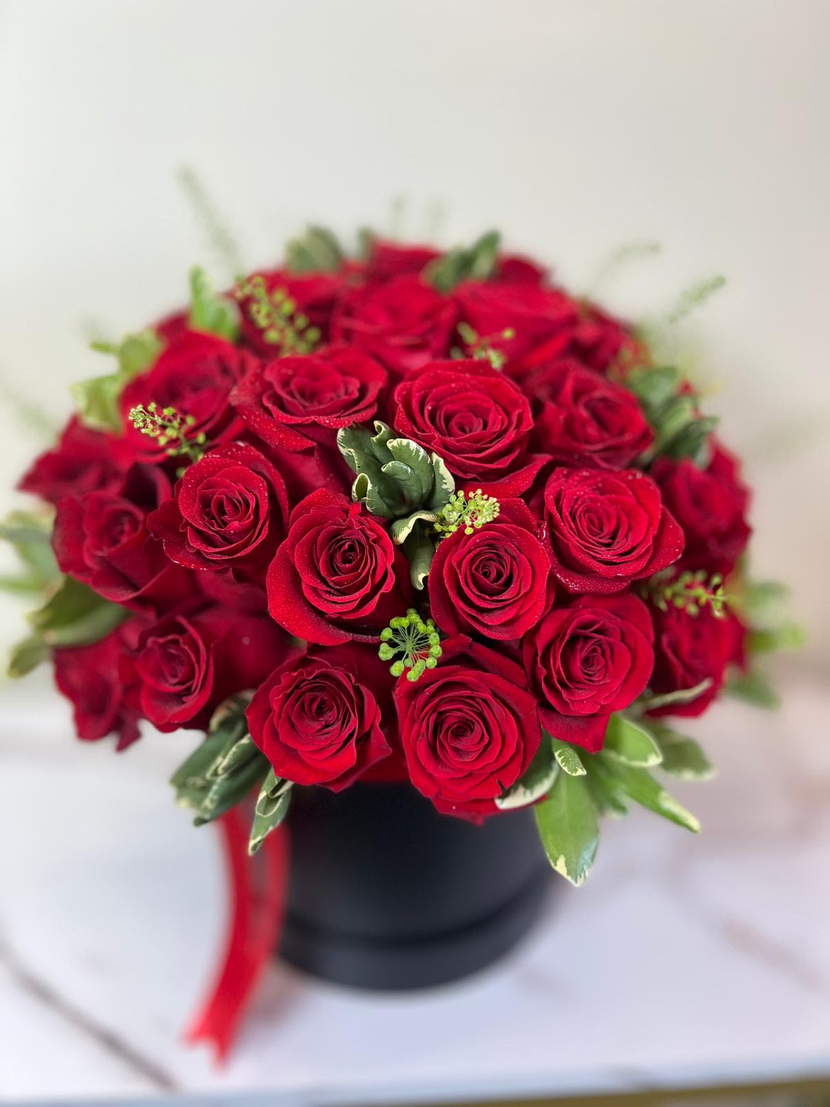 Bouquet of red roses in a black box with a red ribbon