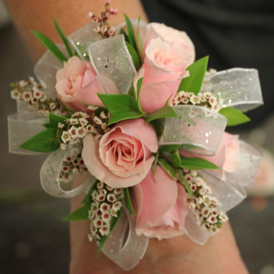 Pink rose corsage with silver ribbon and small white filler flowers