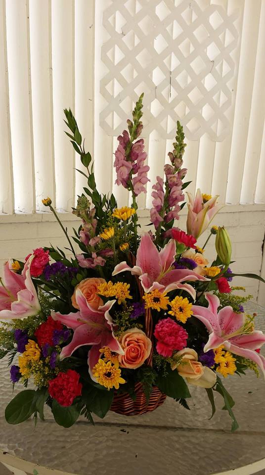 Mixed bouquet with pink lilies, roses, and yellow daisies in a basket