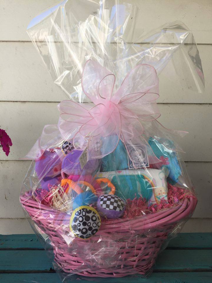 Pink gift basket wrapped in clear cellophane with assorted items inside