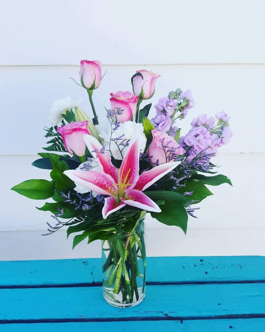 Pink lilies and roses in a clear glass vase