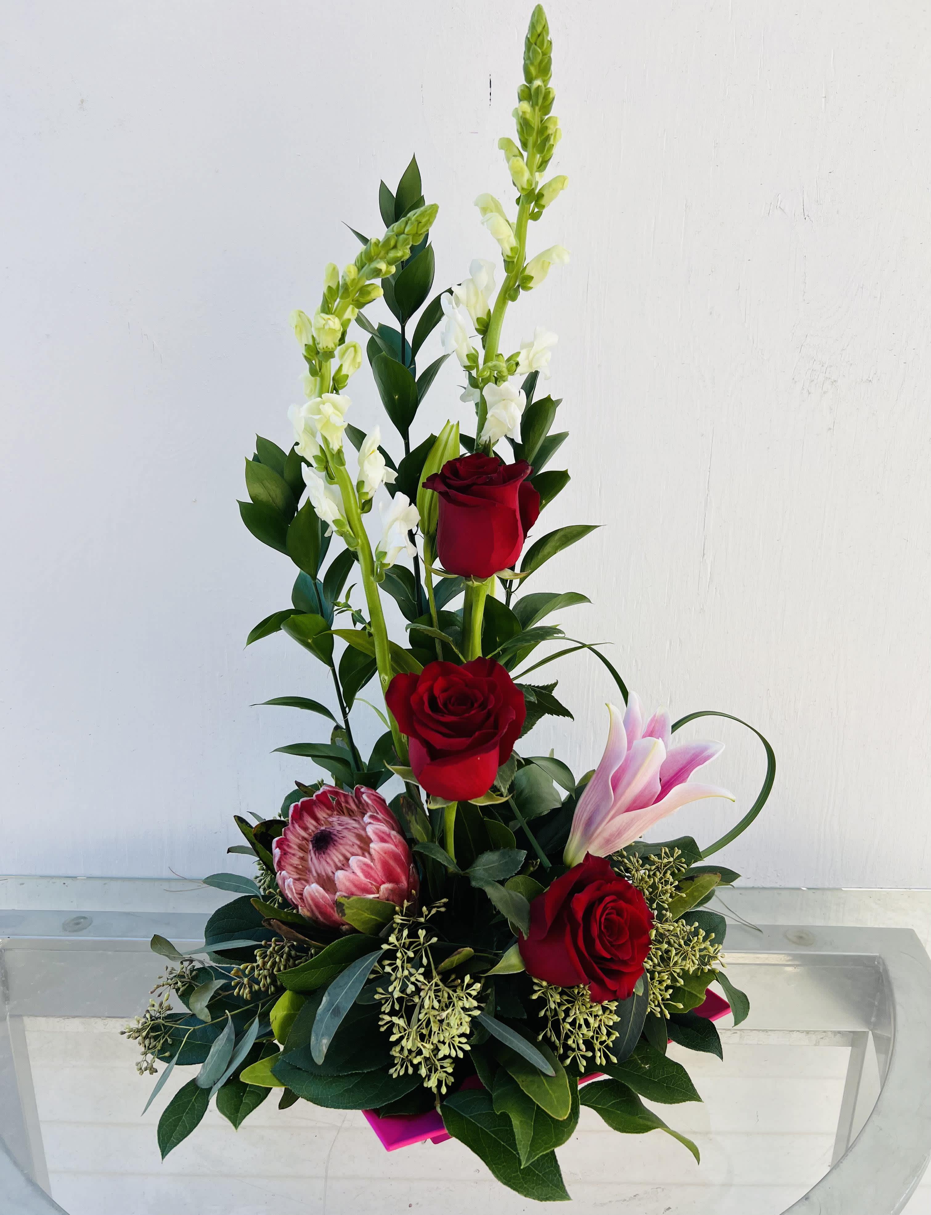 Tall floral arrangement with red roses, pink lily, and white snapdragons