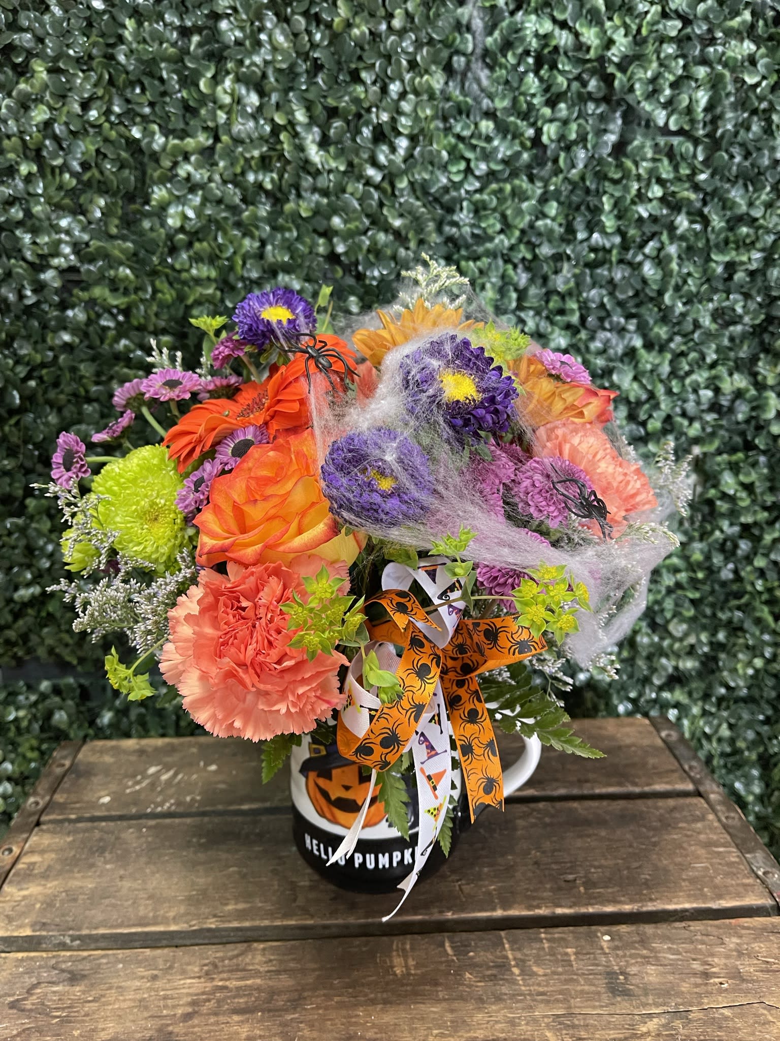 Halloween bouquet in a pumpkin mug with orange, purple, and pink flowers