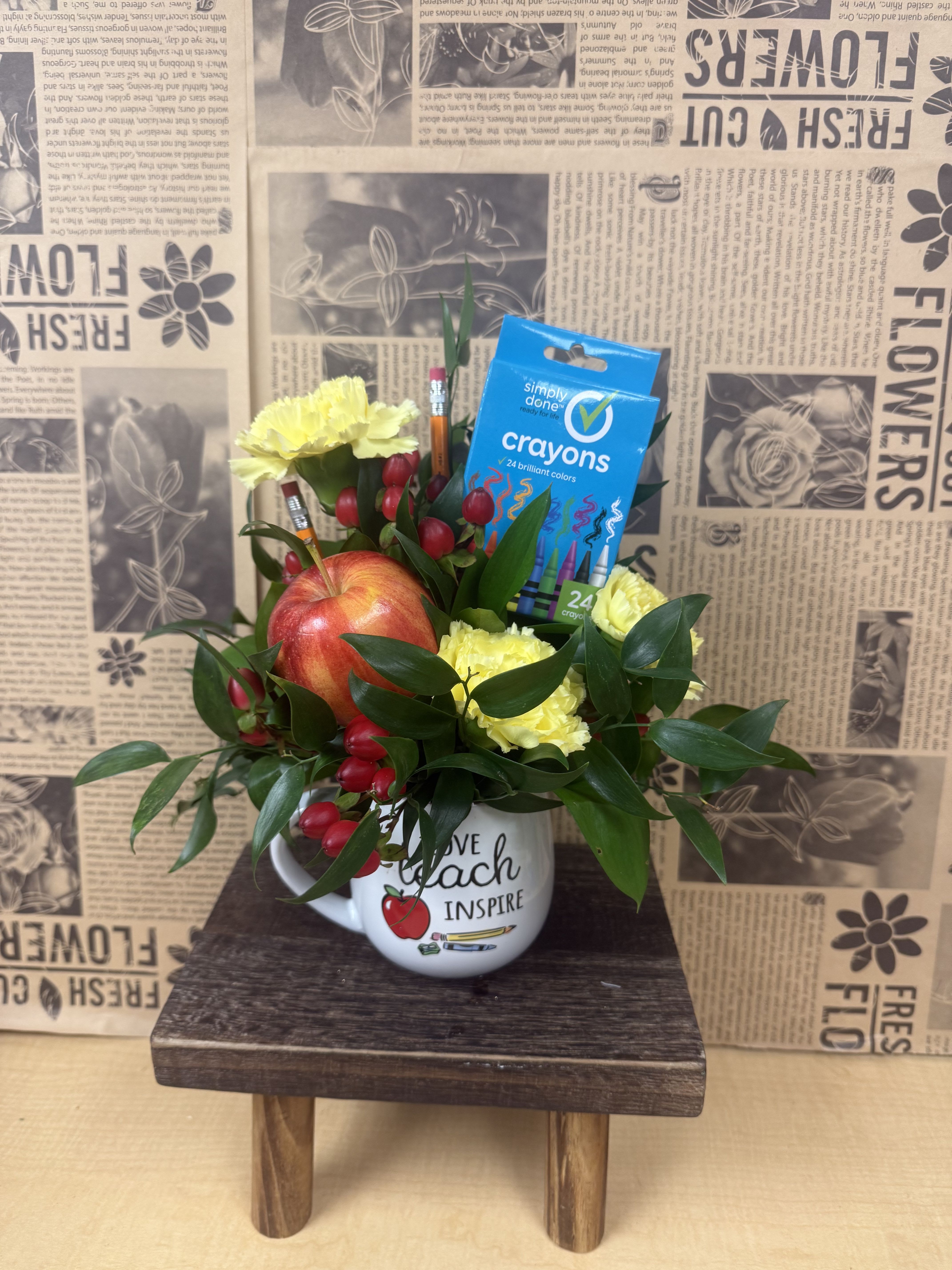 Yellow carnations and an apple in a mug with crayons