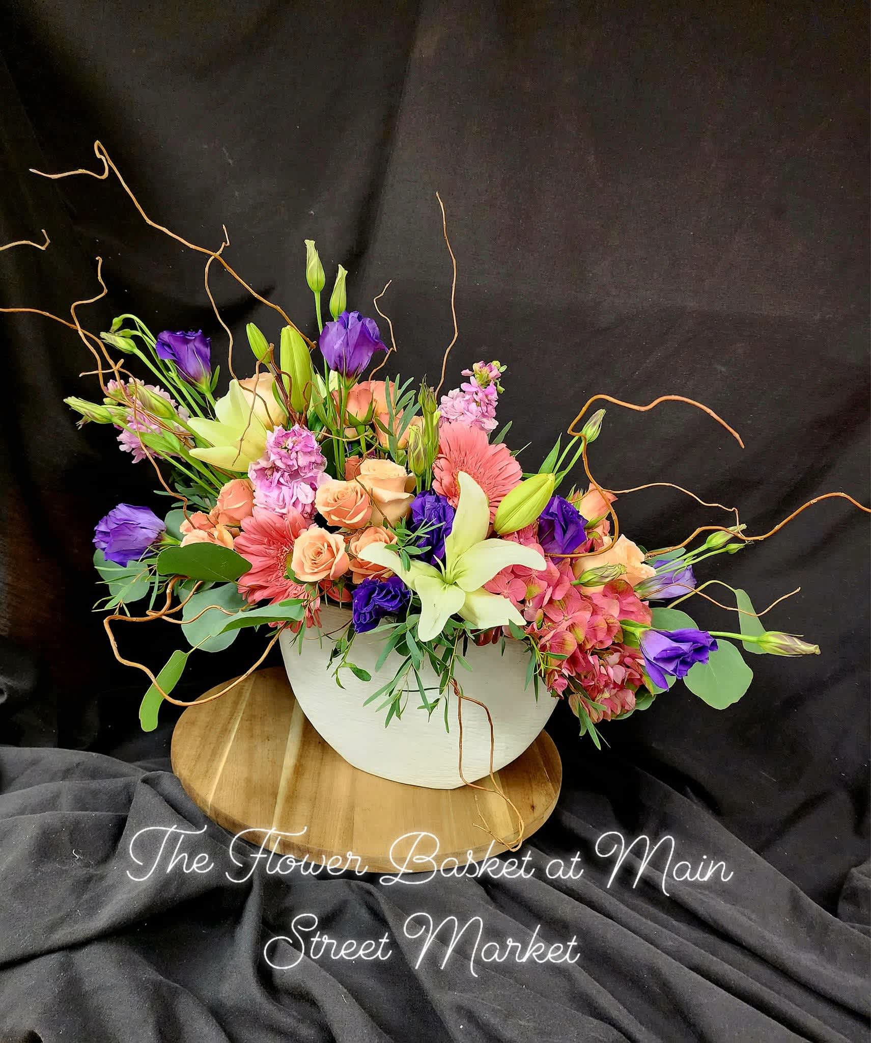 Mixed bouquet in a white bowl vase with pink, purple, and cream flowers