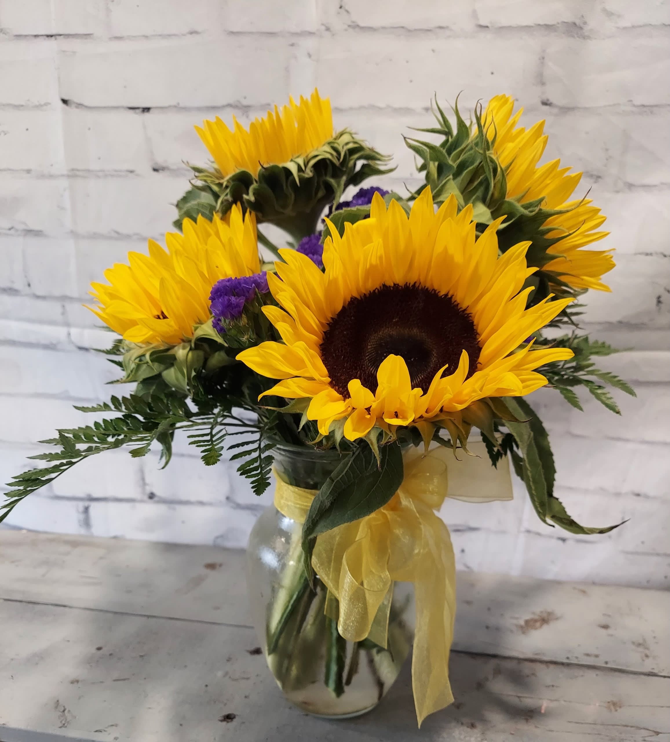 Sunflower bouquet in a glass vase with yellow ribbon