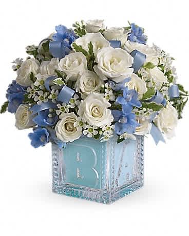 White roses and blue flowers in a decorative cube vase
