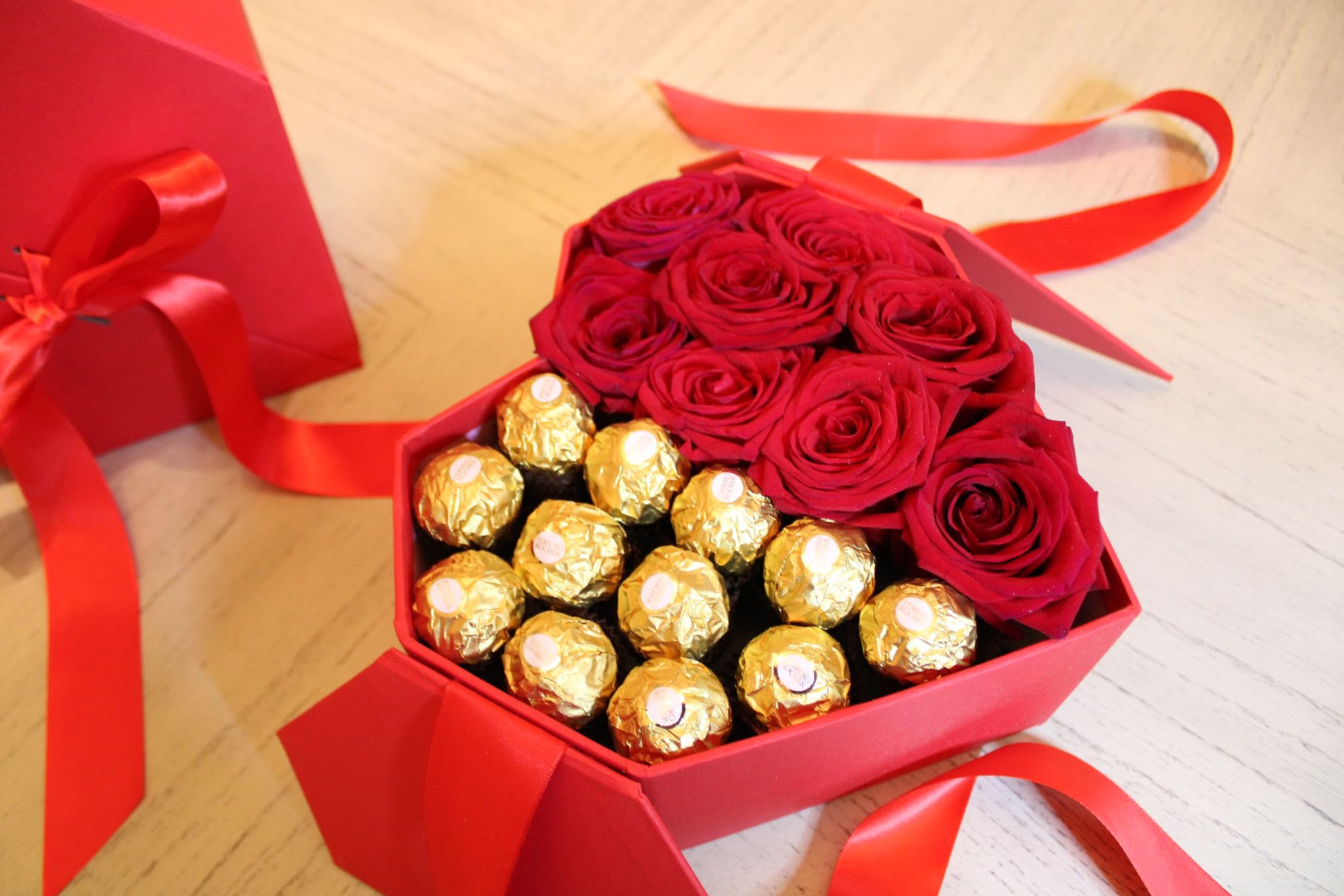 Red roses and gold-wrapped chocolates in a red gift box