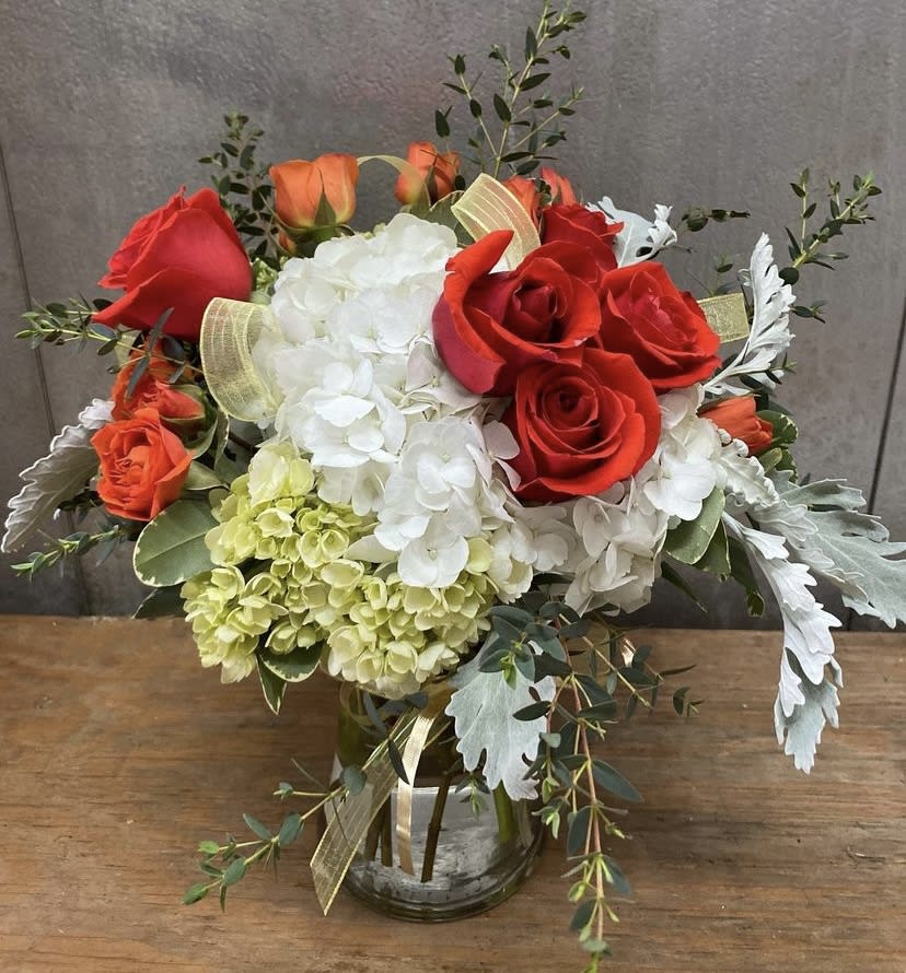 Bouquet of red and orange roses with white hydrangeas in a glass vase