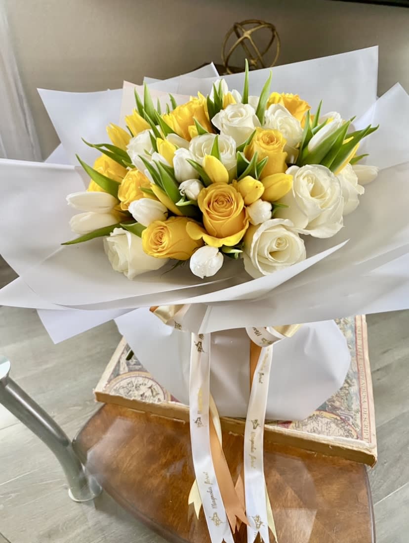 Bouquet of yellow and white roses with white tulips wrapped in white paper