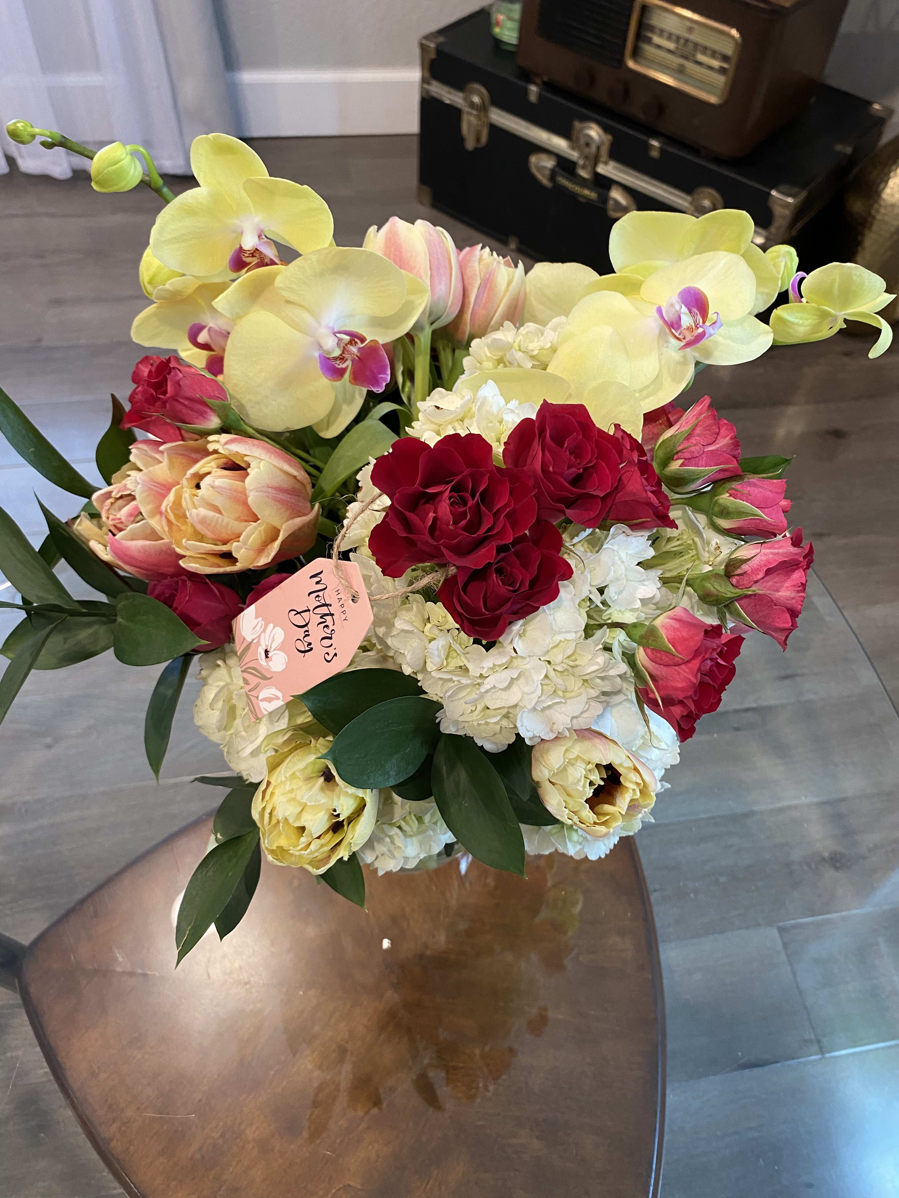 Bouquet of yellow orchids, red roses, and pink tulips