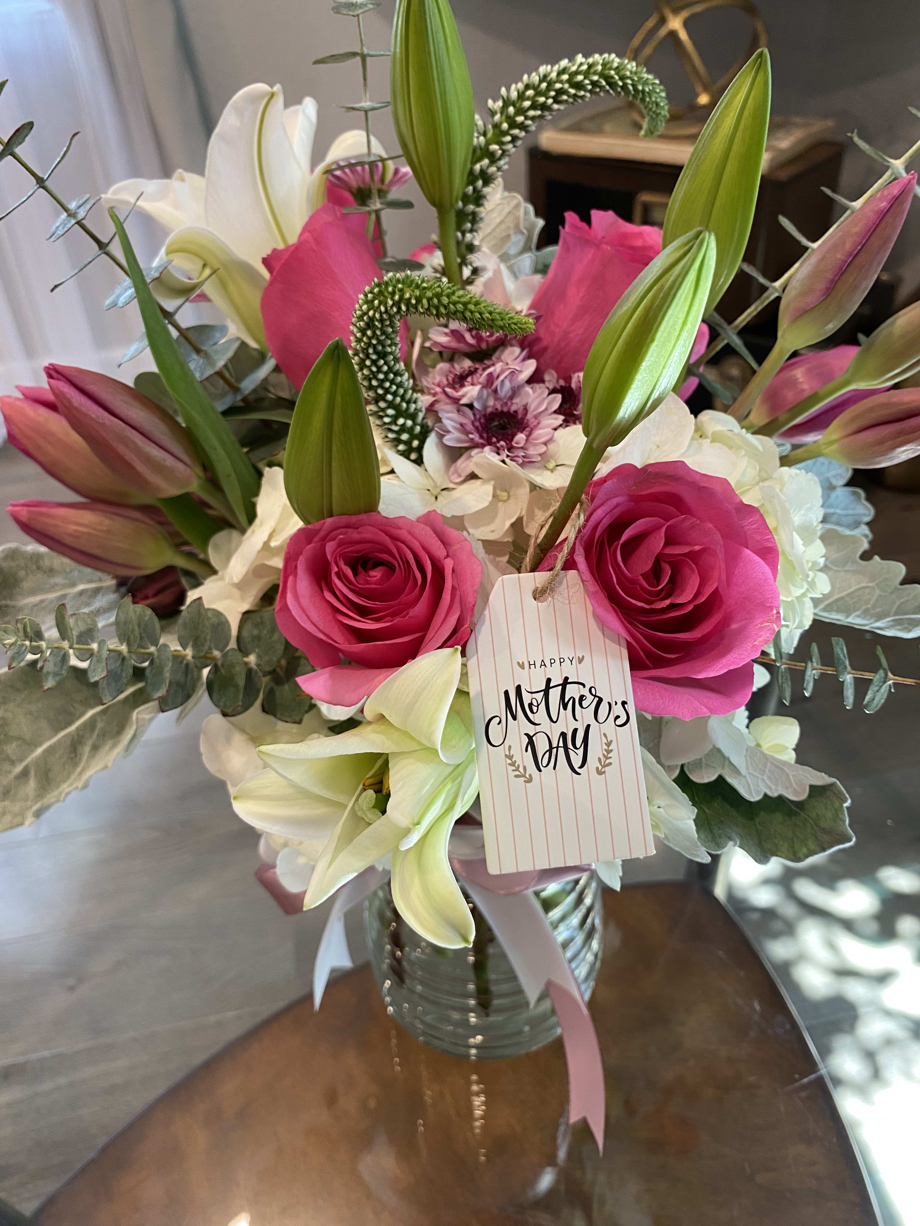 Bouquet of pink roses and white lilies in a glass vase with a Mother's Day tag