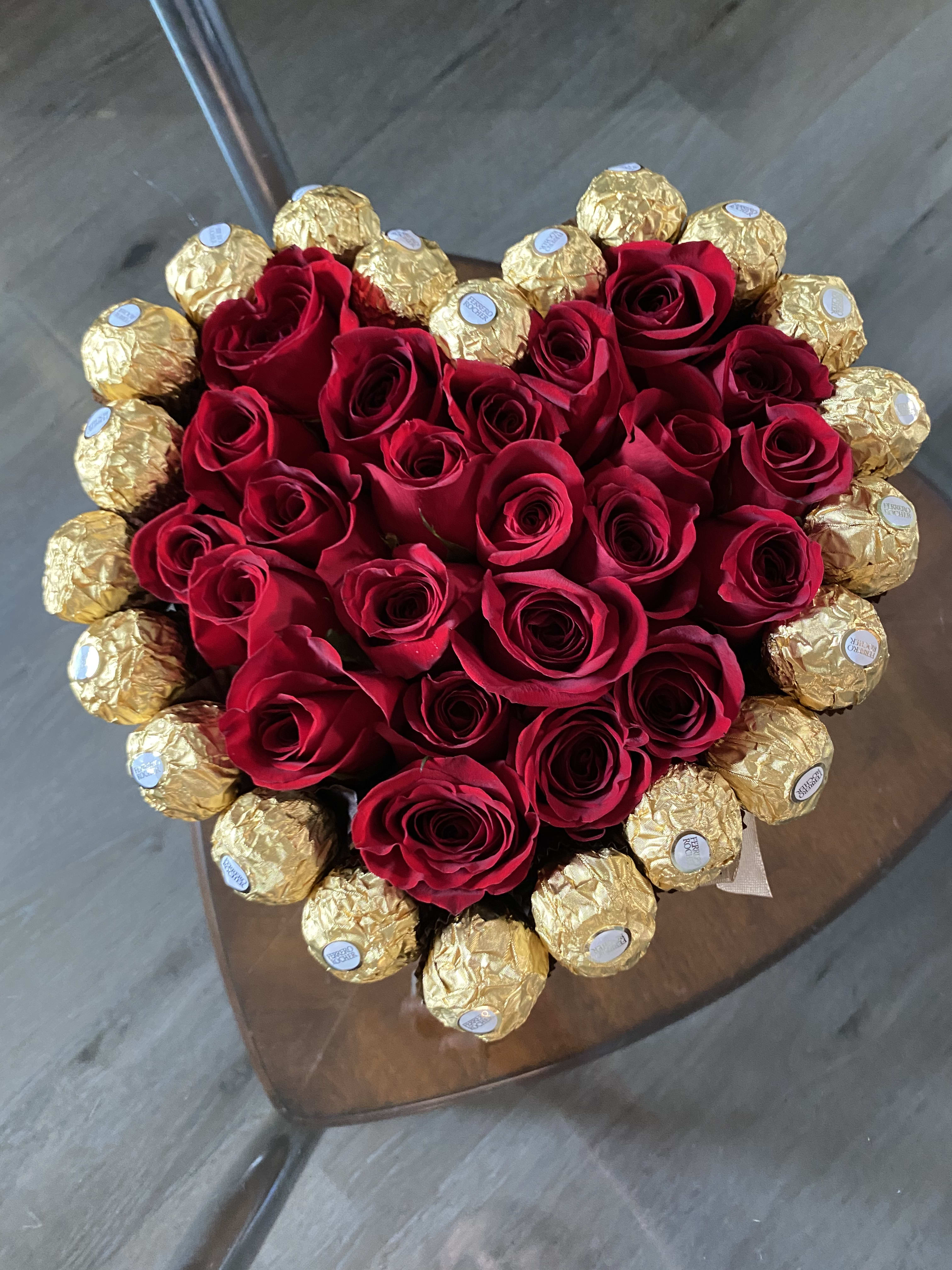 Heart-shaped bouquet of red roses surrounded by gold-wrapped chocolates