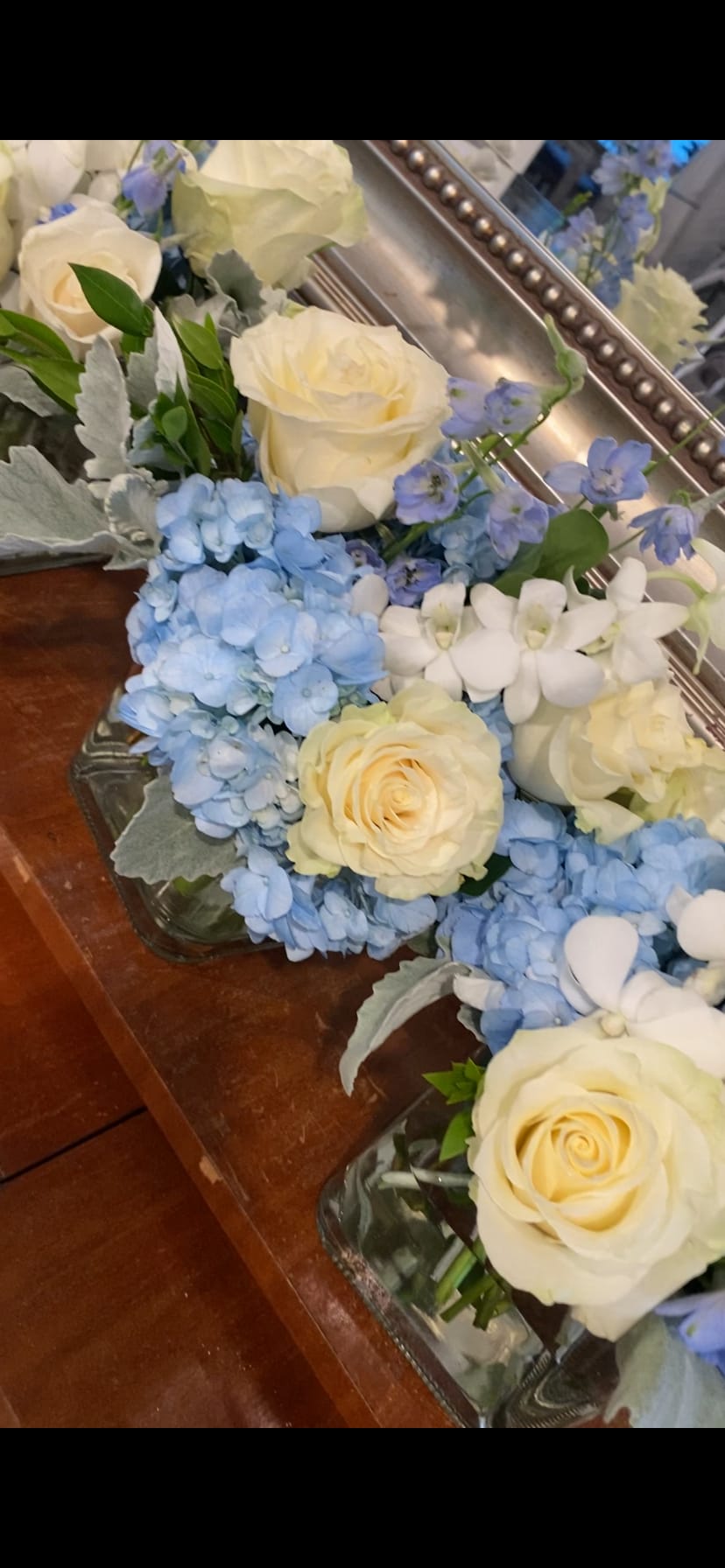 Cream roses and blue hydrangeas arranged in glass containers