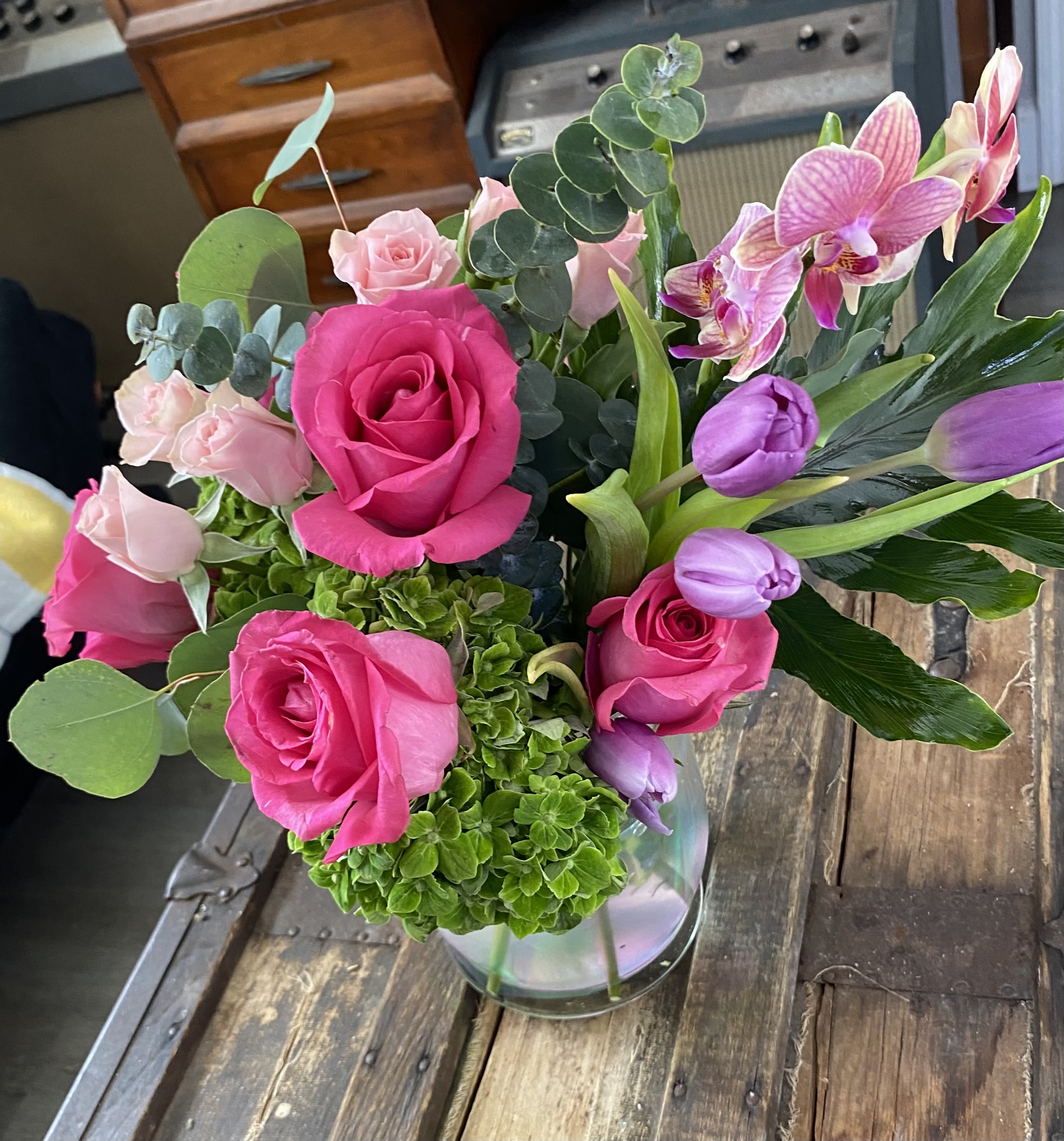 Bouquet of pink roses and purple tulips in a clear glass vase