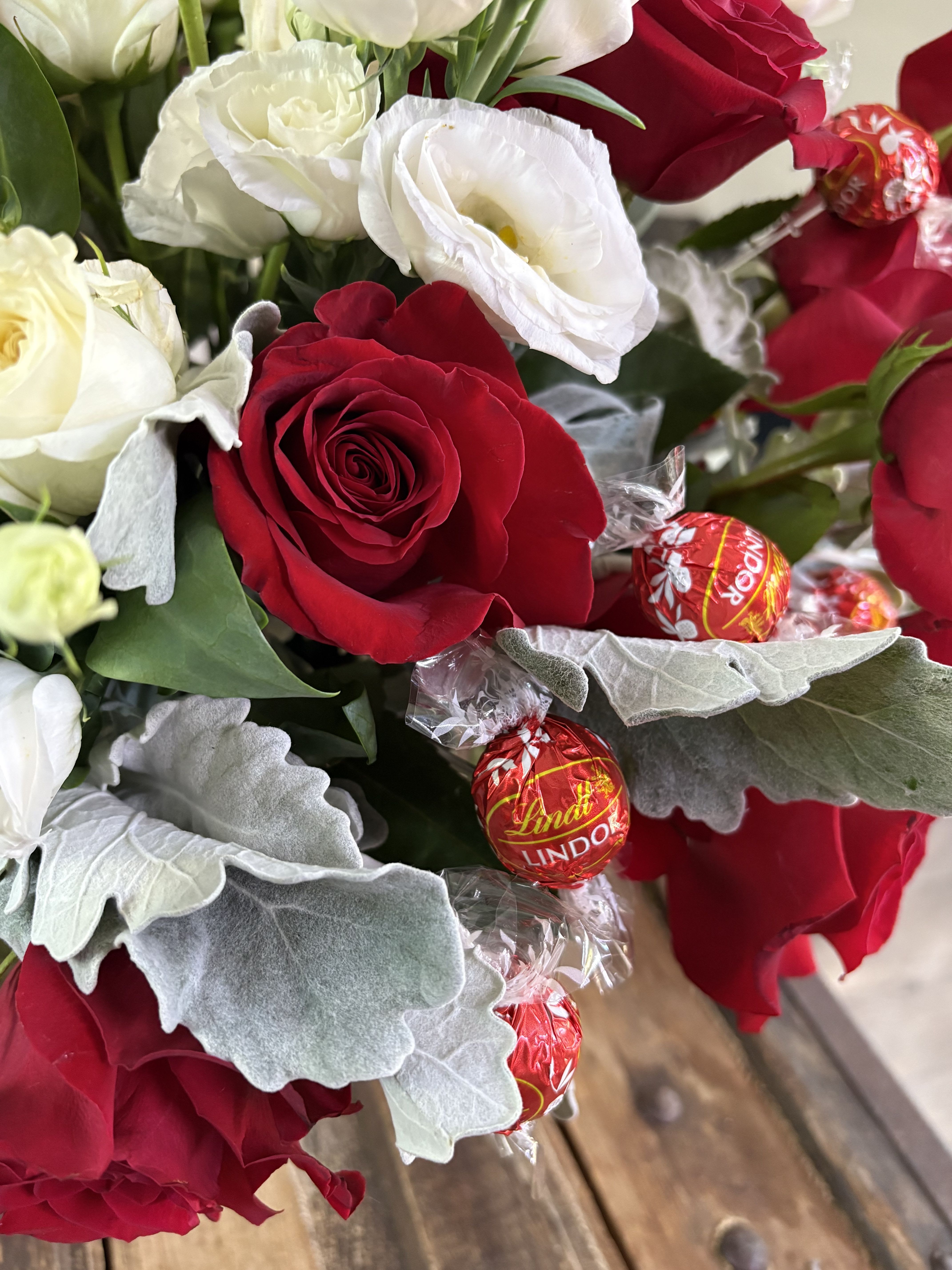 Bouquet of red and white roses with wrapped chocolates