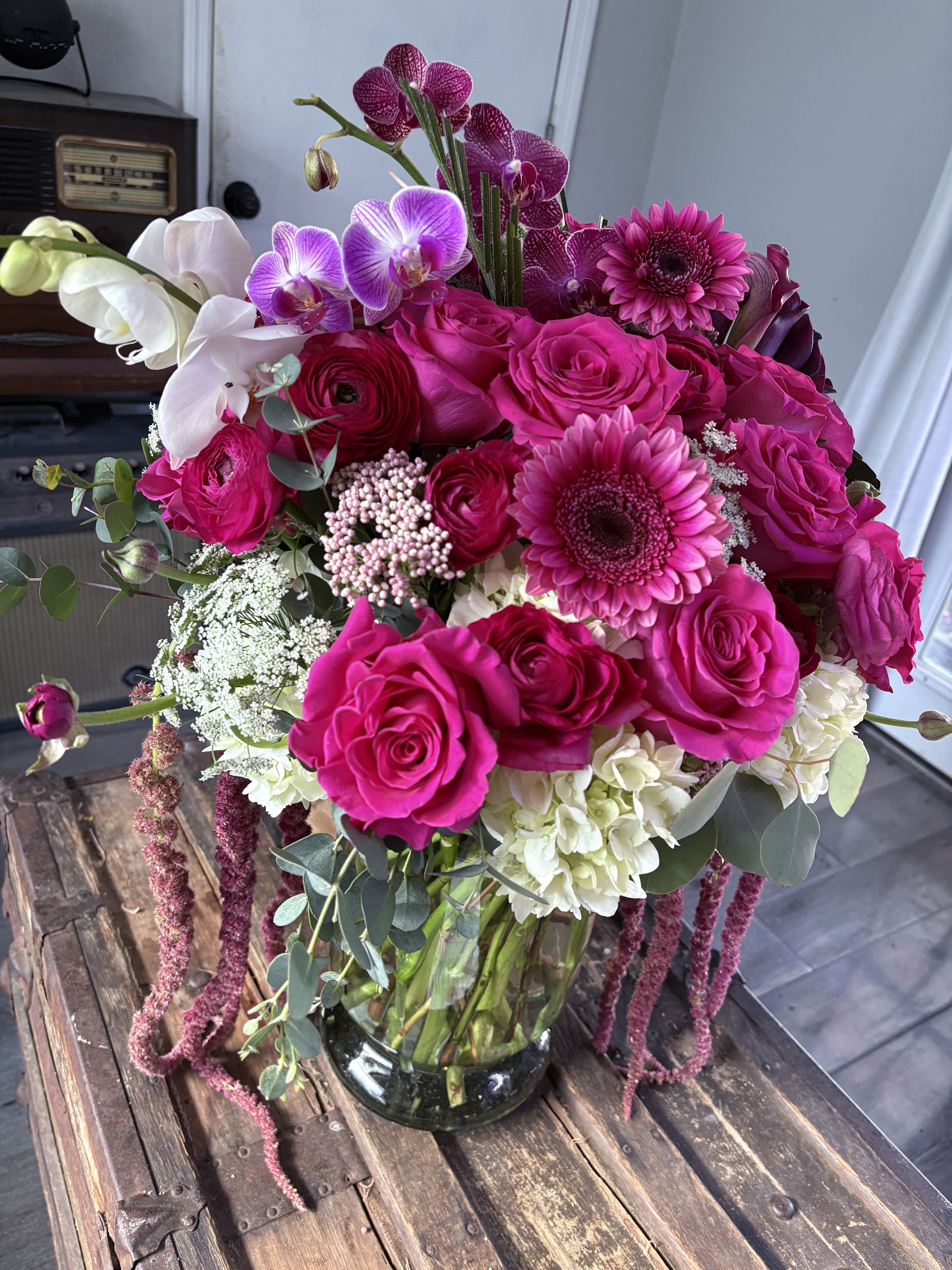 Bouquet of hot pink roses, orchids, and gerbera daisies in a glass vase