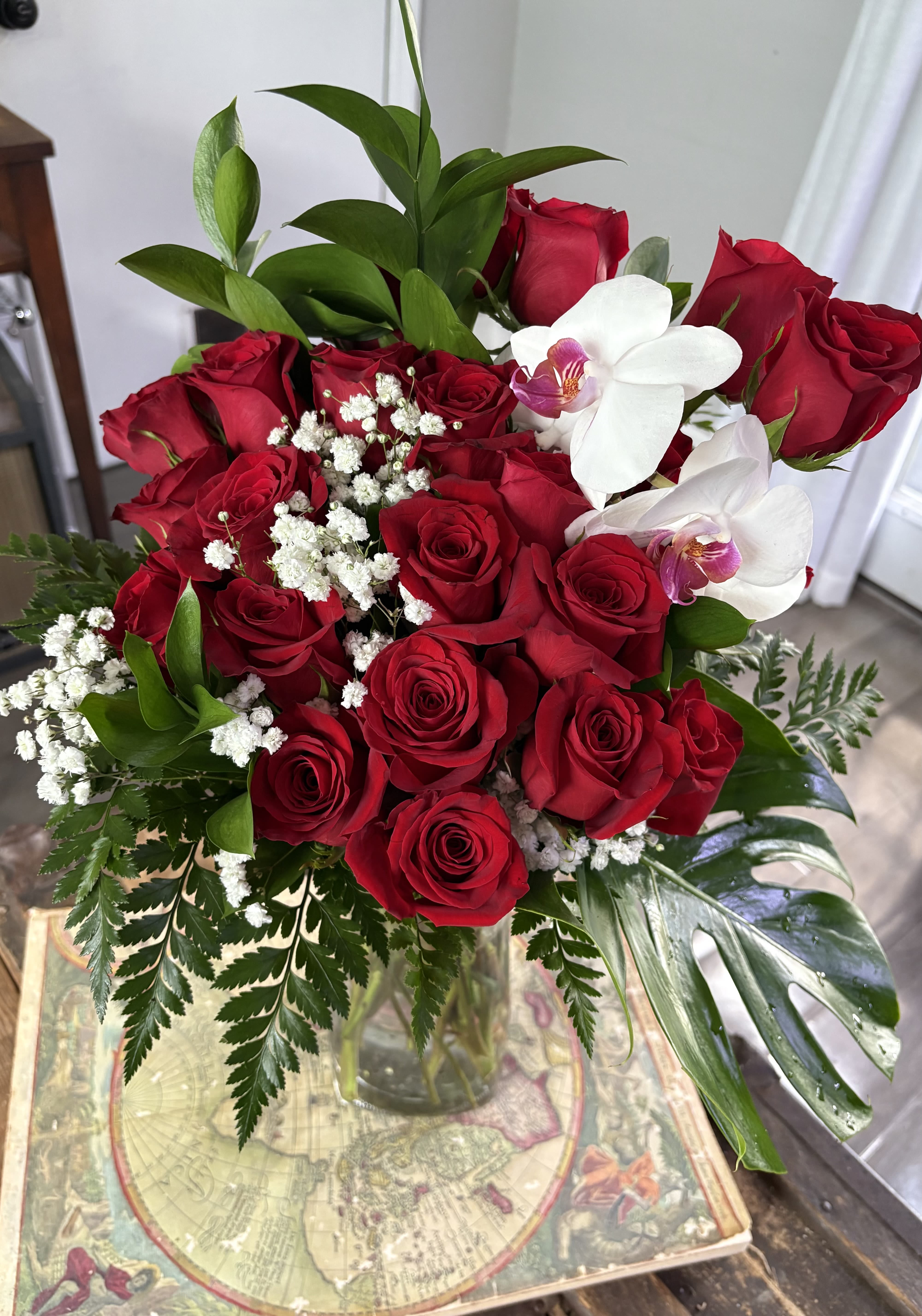 Bouquet of red roses with white orchids and baby's breath in a glass vase
