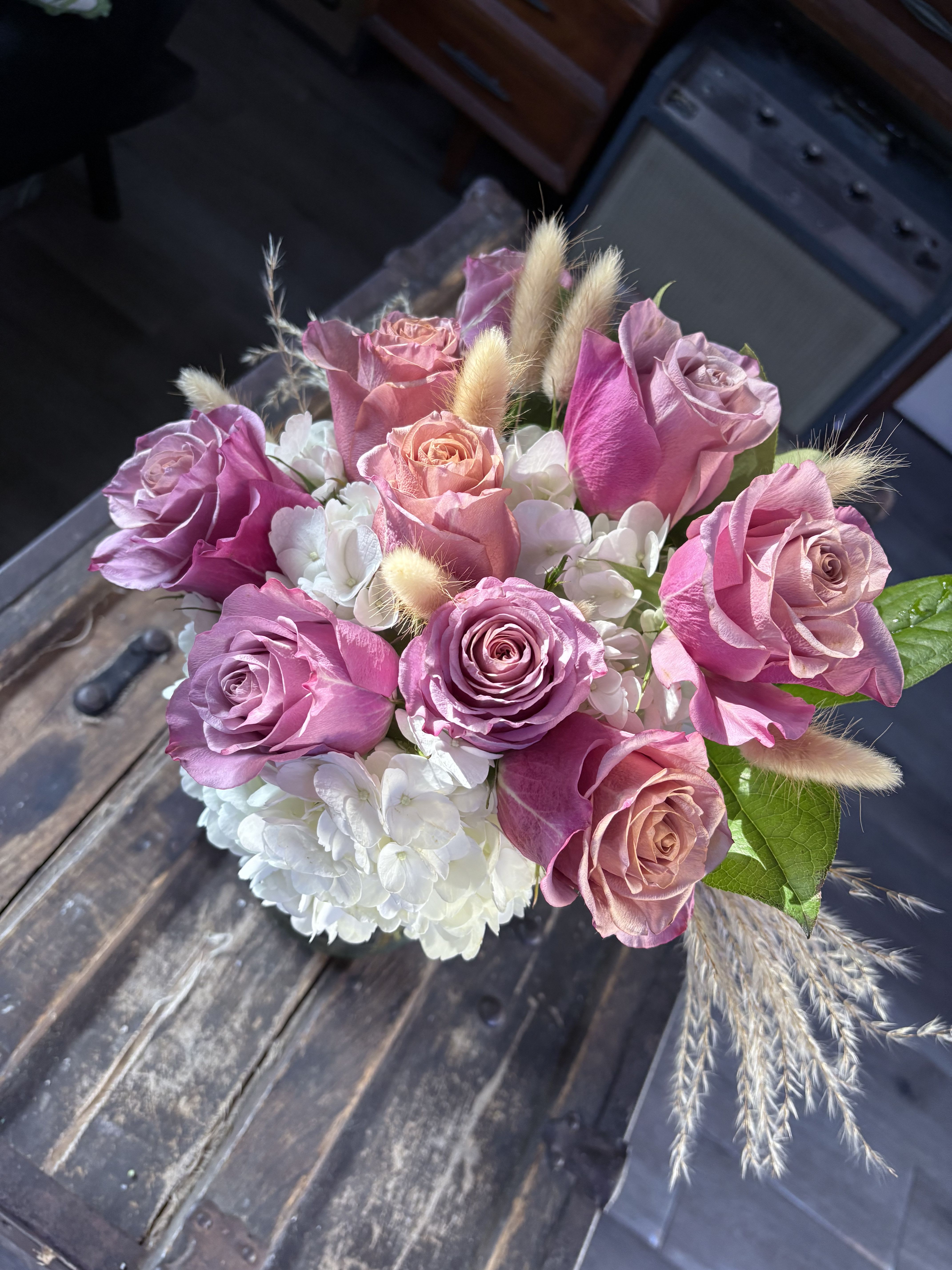 Pink and lavender roses with white hydrangeas in a compact bouquet