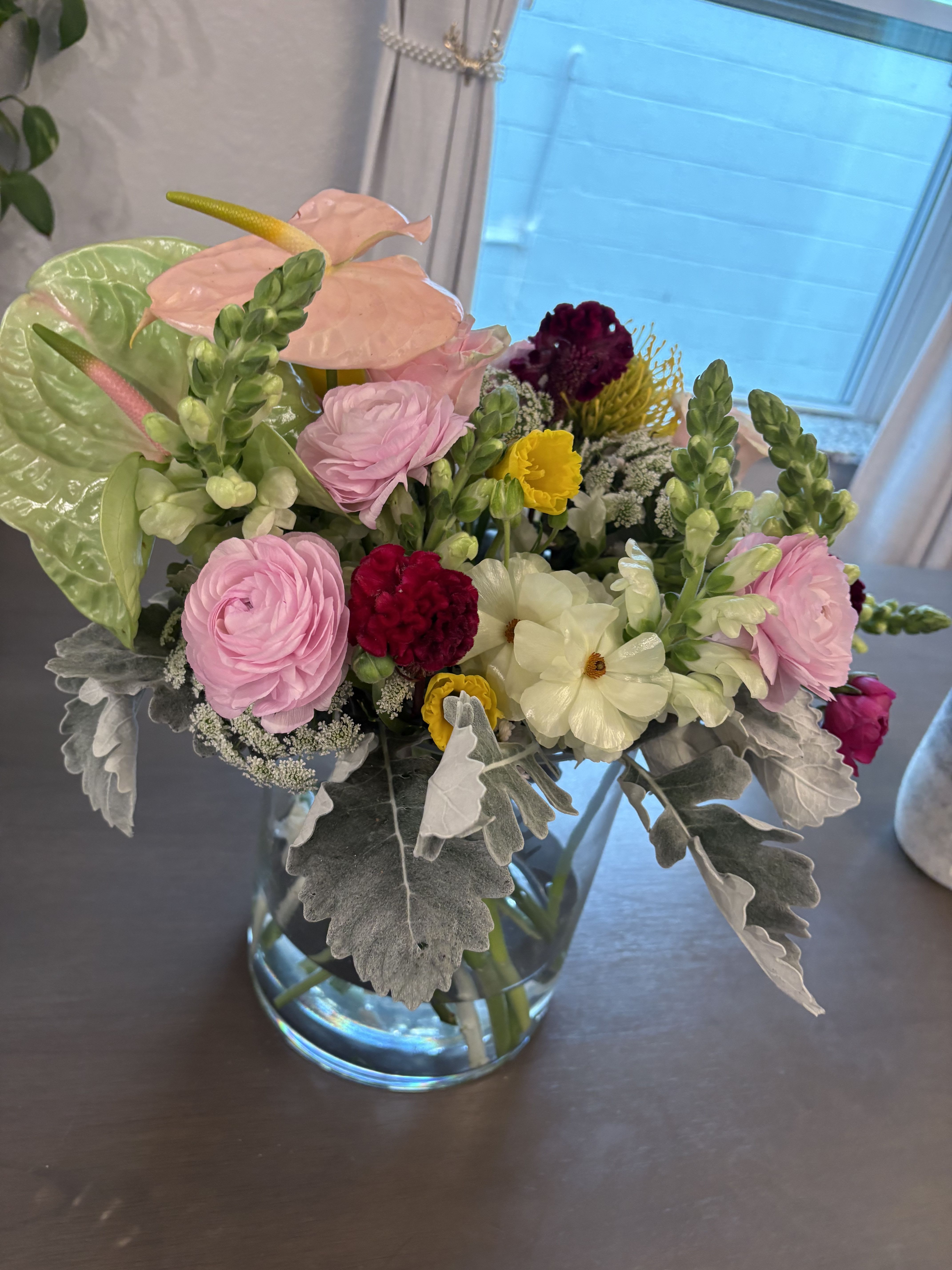 Mixed bouquet in a clear glass vase with pink, white, and yellow blooms