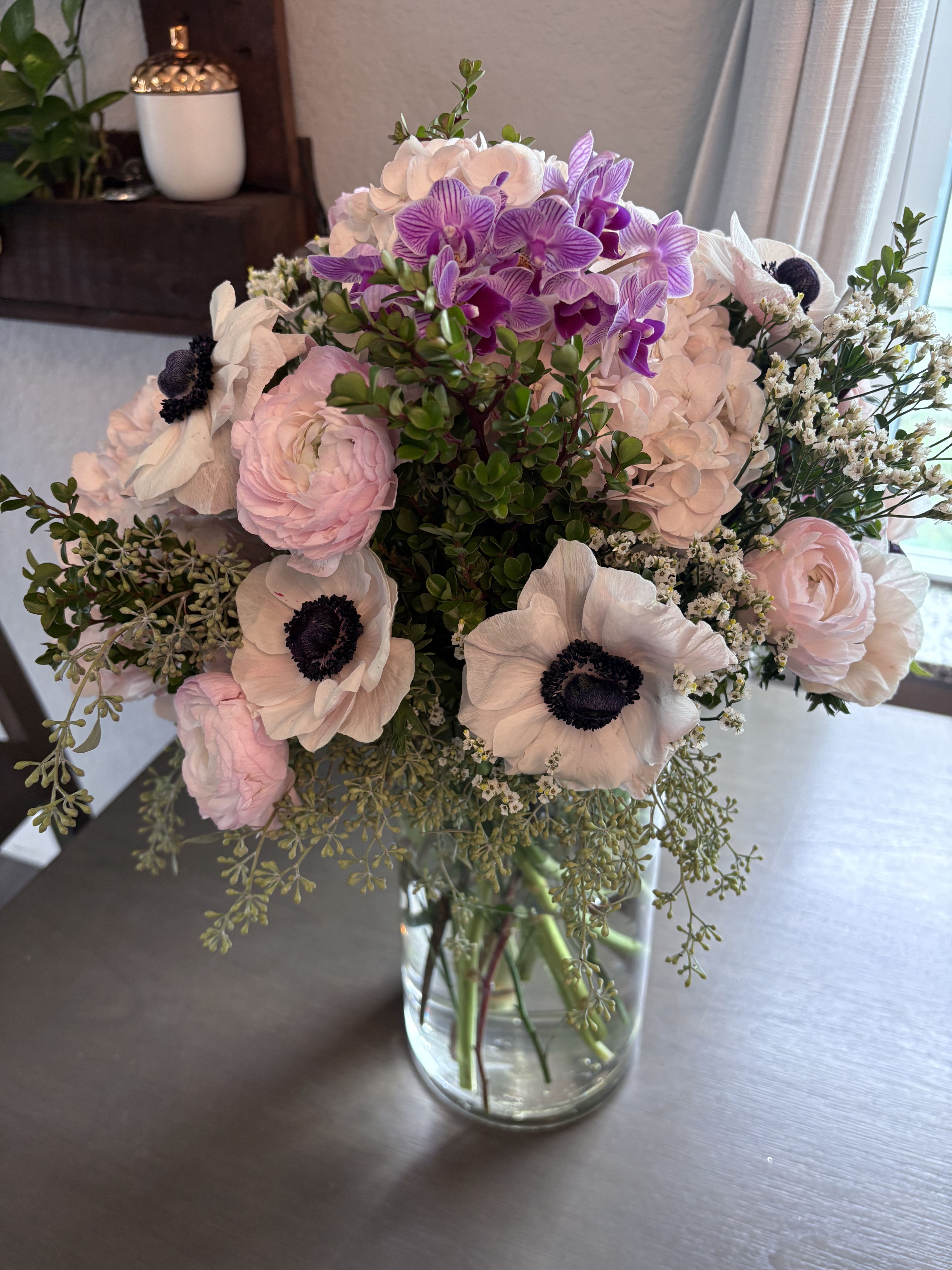 Bouquet of pale pink and purple flowers in a clear glass vase