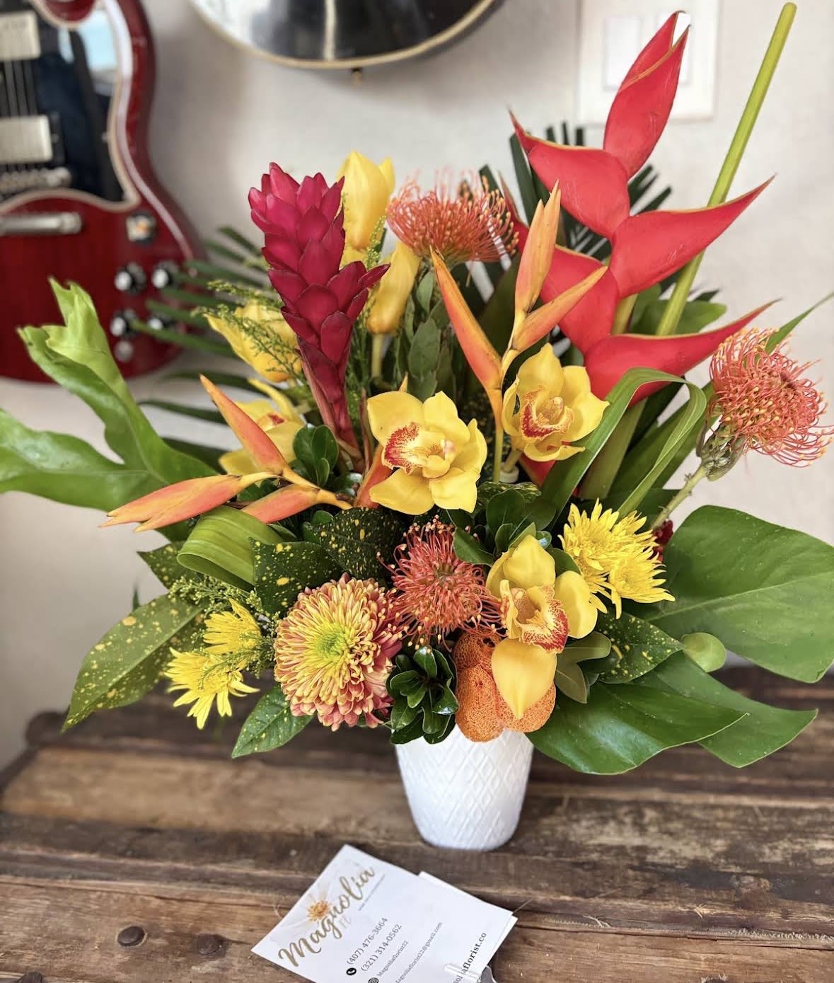 Tropical bouquet with red heliconia and yellow orchids in a white vase
