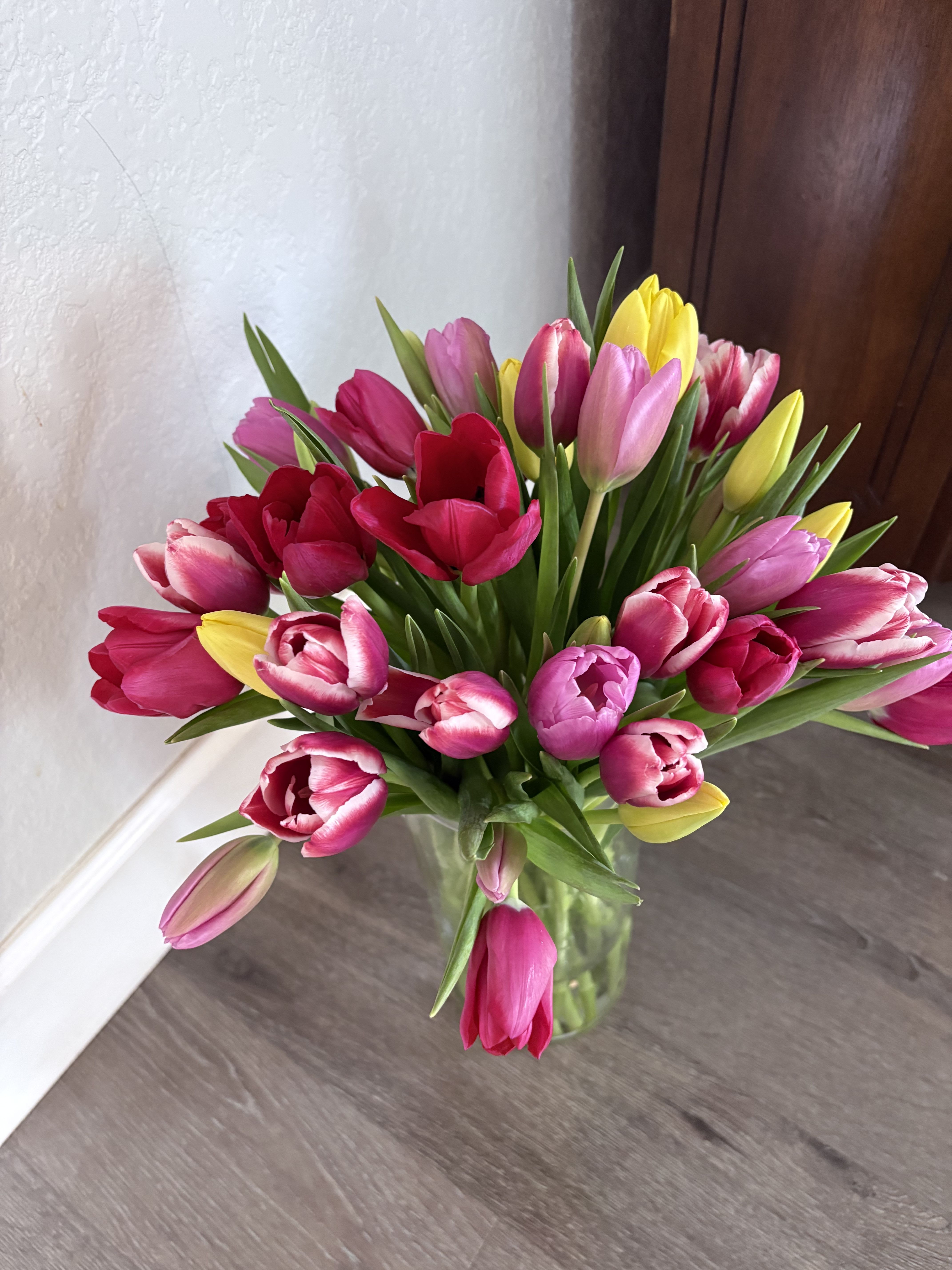 Bouquet of pink, red, and yellow tulips in a clear glass vase