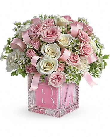 Pink and white rose arrangement in a decorative glass vase with ribbon