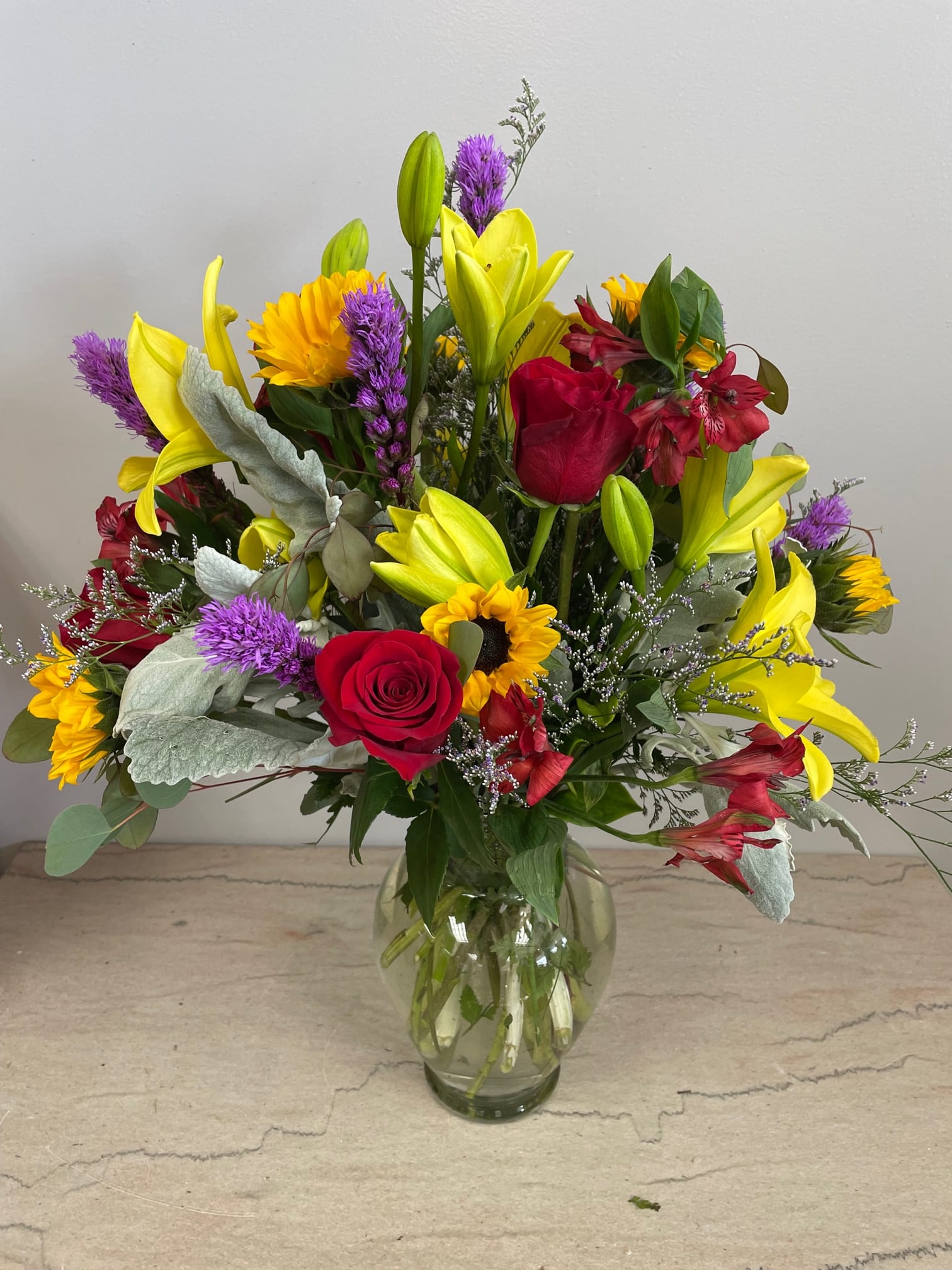 SUNRISE ON THE CHOPTANK - Lilies, sunflowers and roses combine to make a striking display evocative of lazy summer days spent along the Choptank.  Bursting forth with blooms and memories, this creation will bring a smile.