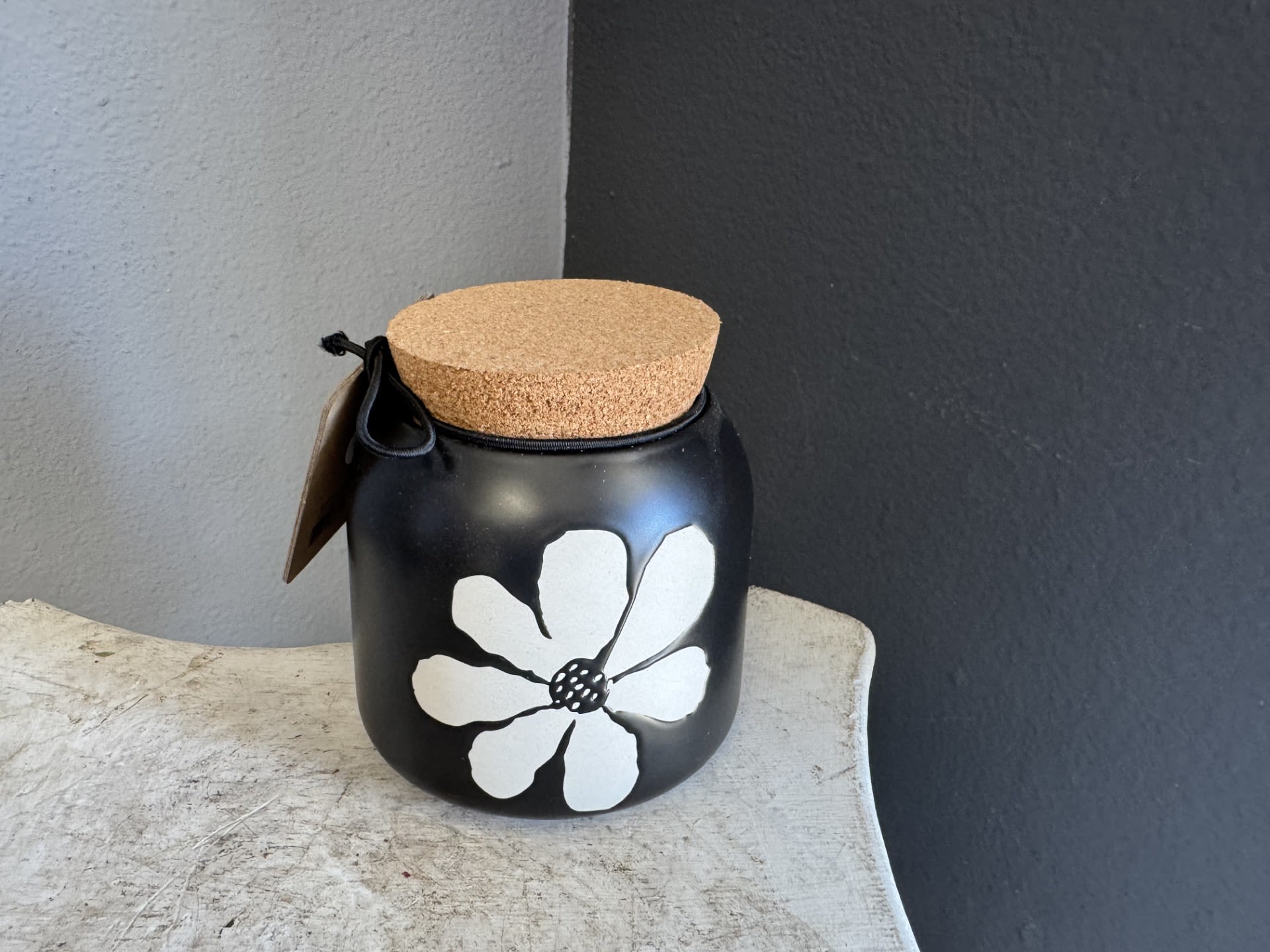 Black jar with a cork lid and white flower design