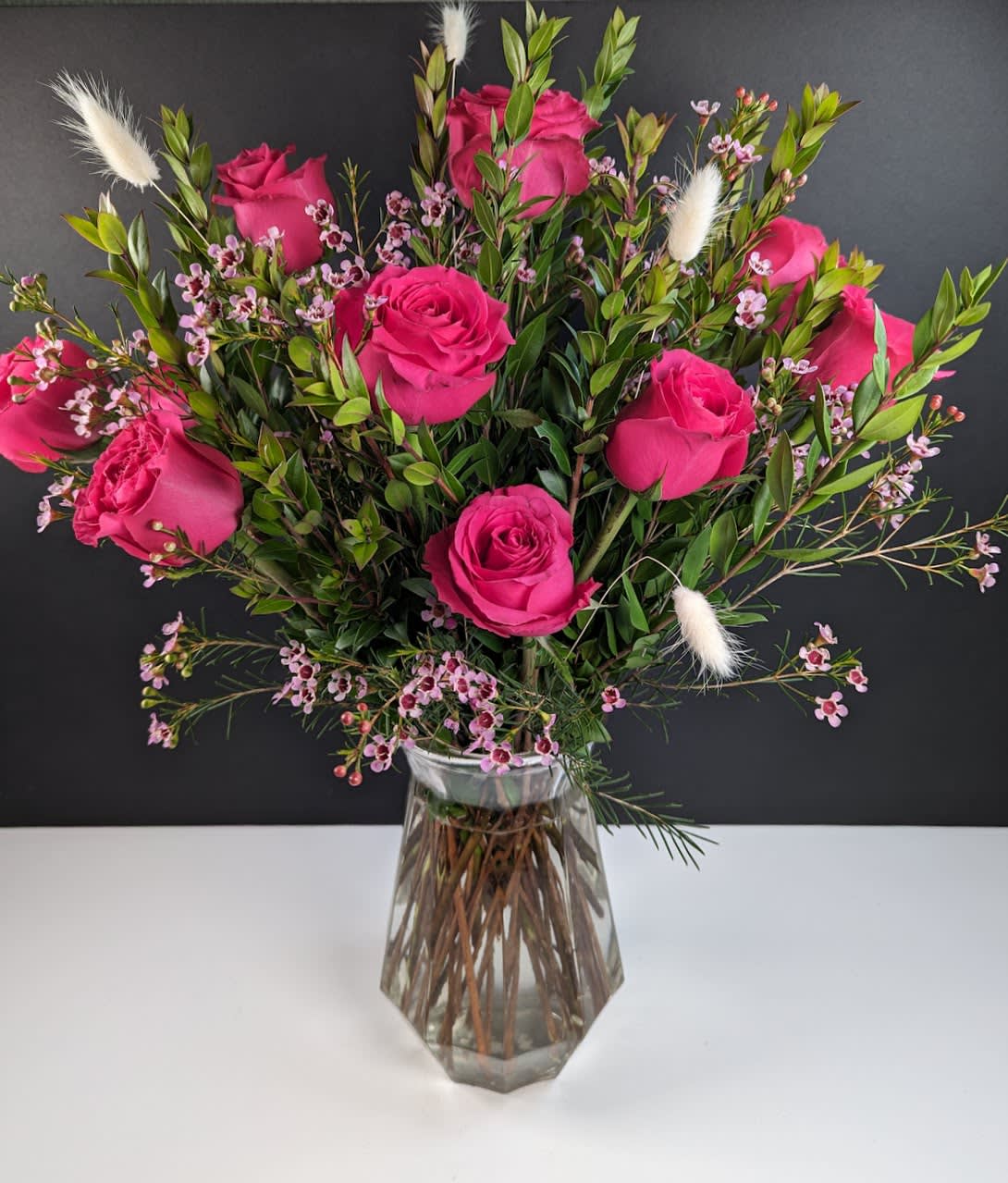 Pink roses arranged in a clear glass vase with small filler flowers