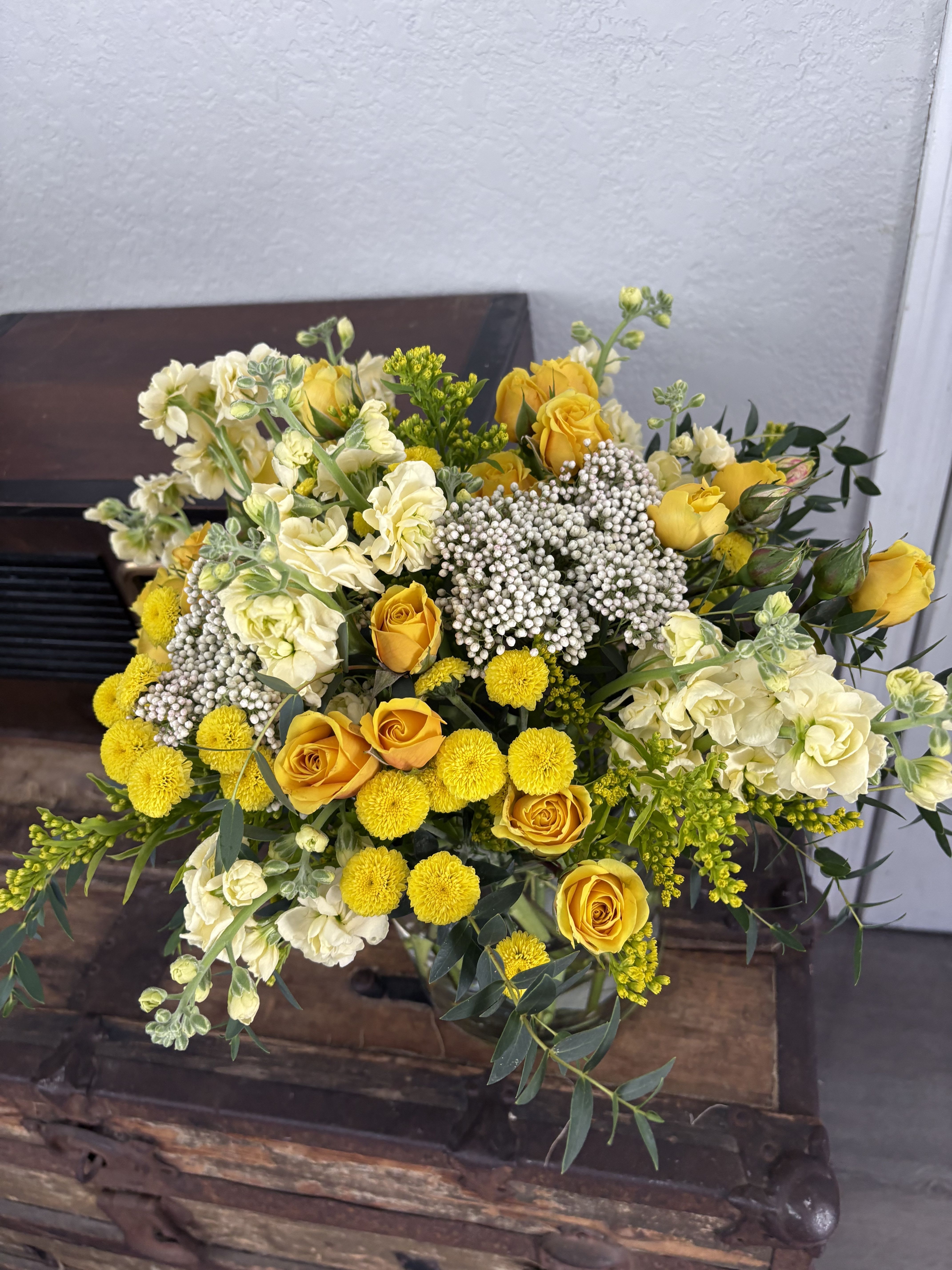 Yellow roses and cream flowers arranged in a bouquet