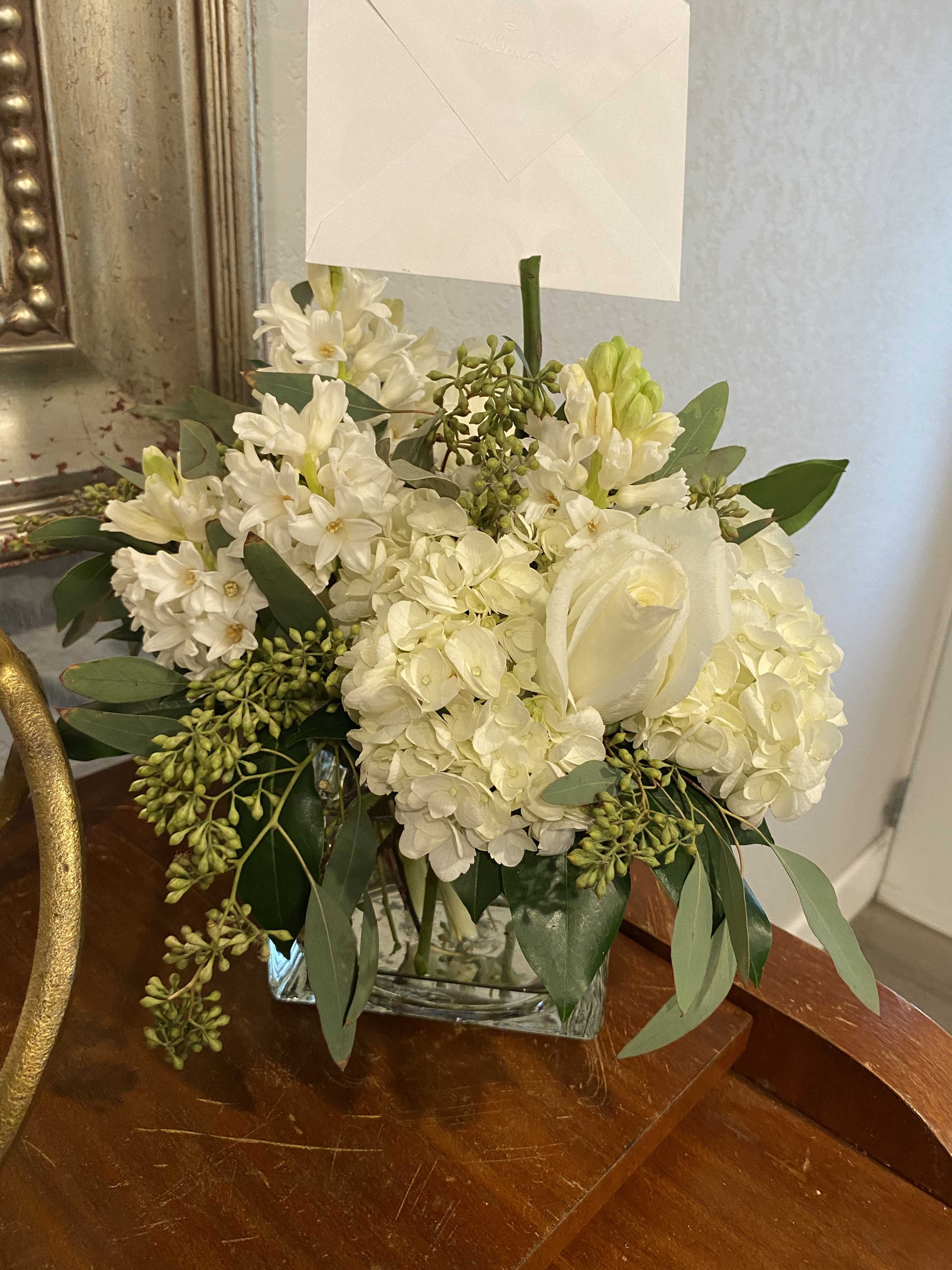 White floral arrangement in a clear glass vase with a card holder