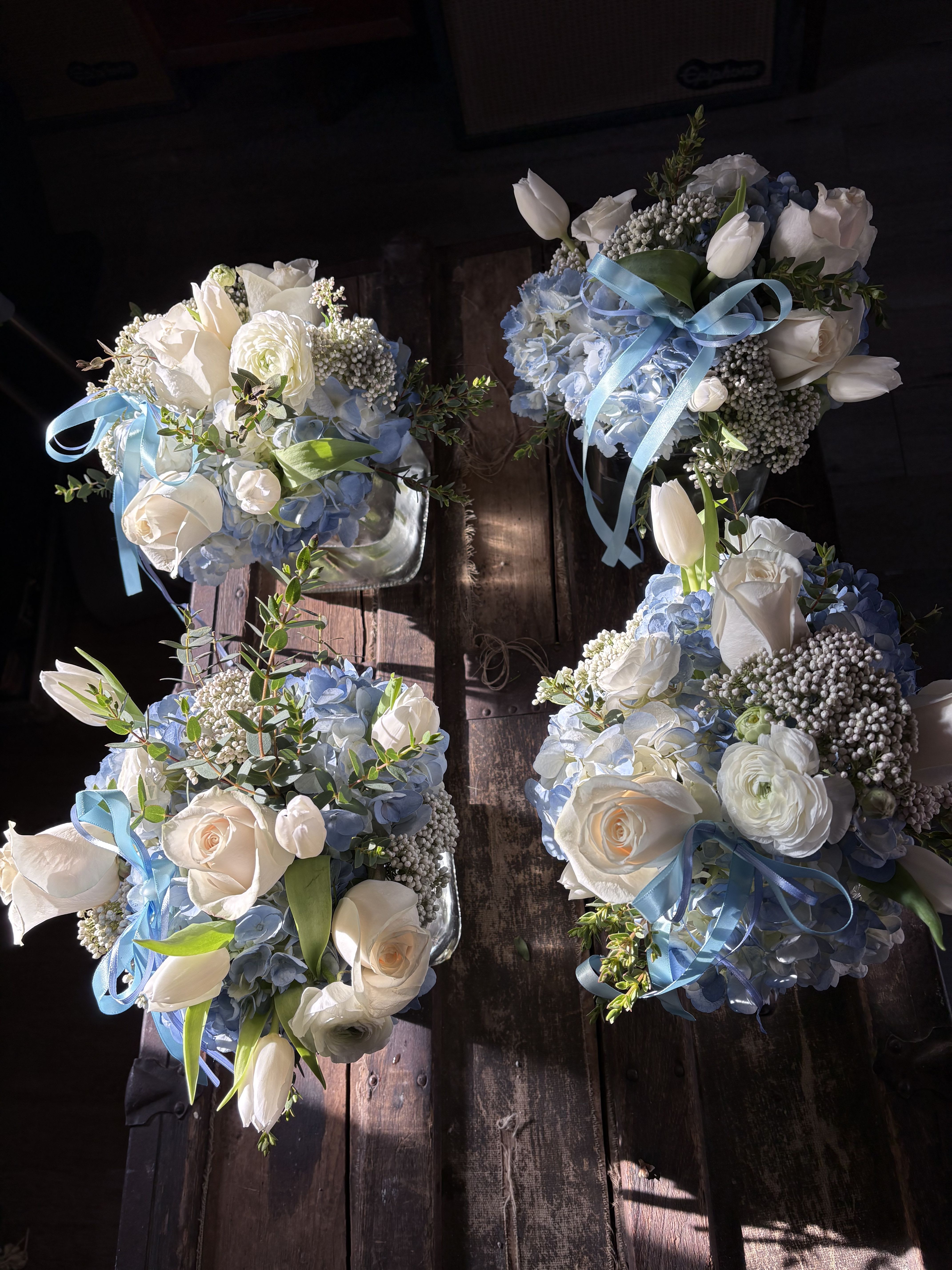 Four blue and white floral bouquets with ribbon on a wooden surface