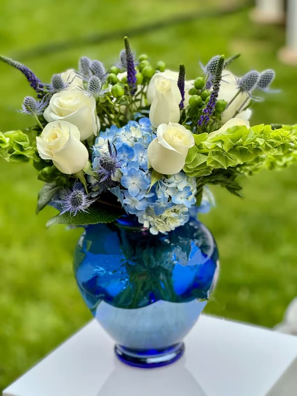 Blue and white floral arrangement in a cobalt glass vase