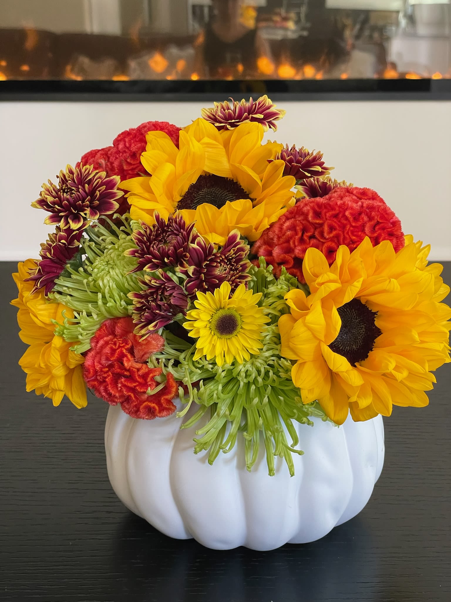 Sunflowers and mixed chrysanthemums arranged in a white pumpkin vase