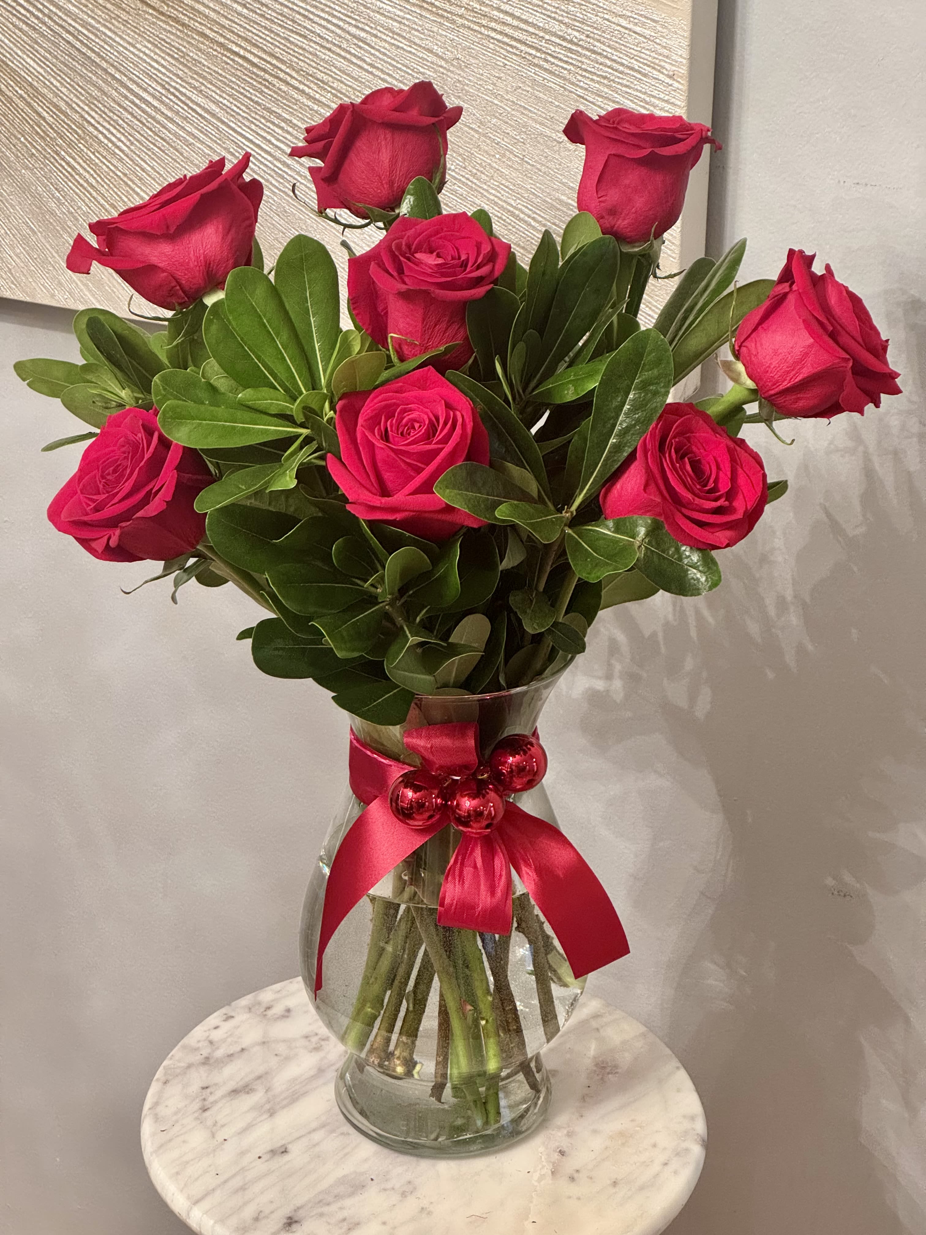 Bouquet of red roses in a glass vase with a pink ribbon