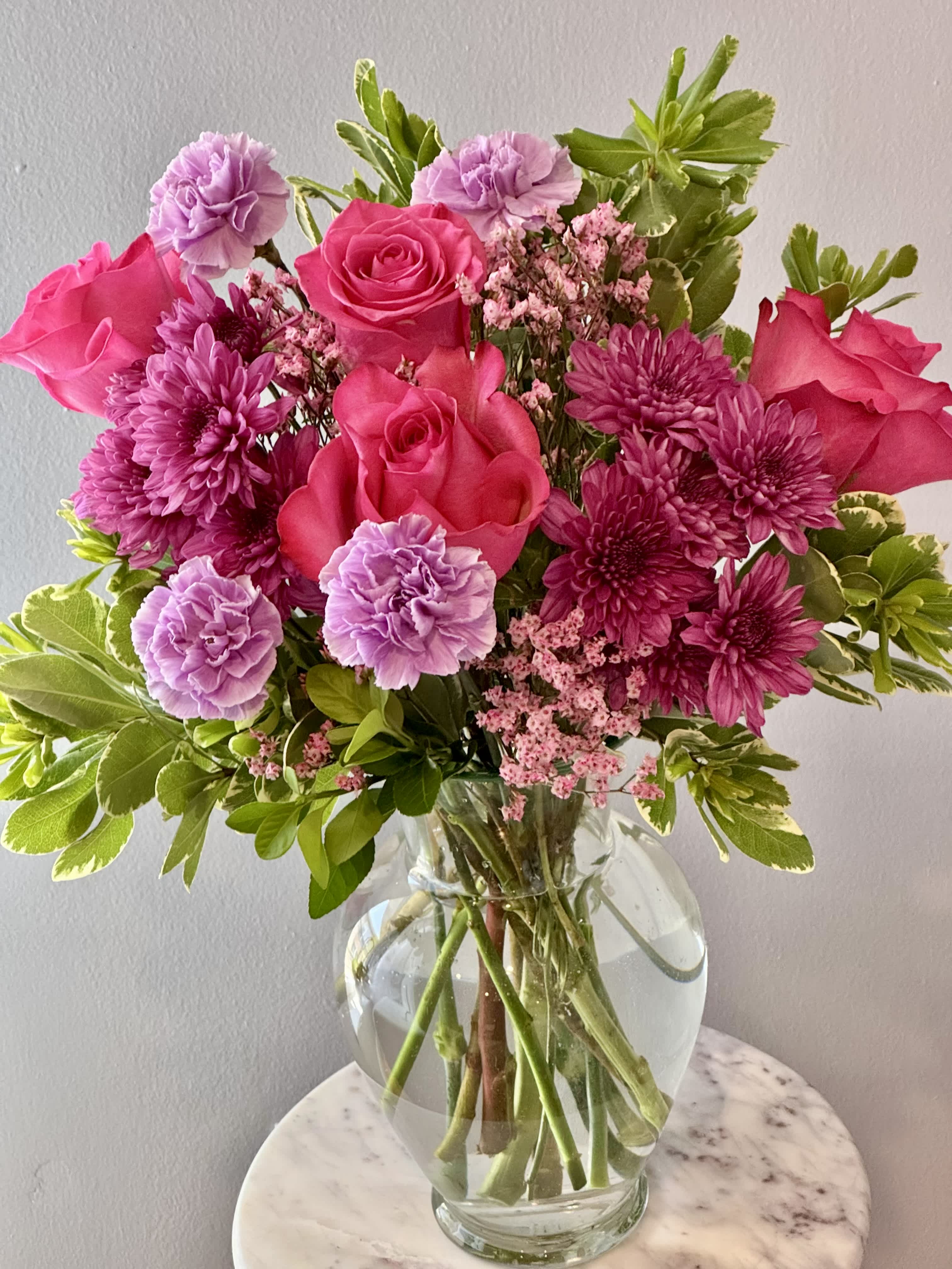 Pink roses and purple flowers in a clear glass vase